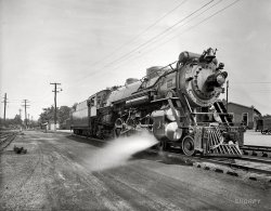 Washington, D.C., or vicinity circa 1926. "Southern R.R. Co. Crescent Locomotive 1396." View full size. National Photo Company Collection glass negative.
Queen Crescent LimitedA short history of the Queen Crescent Limited.
1396, 1926
Still puffin&#039;I have lived in Chattanooga and more than once rode on the excursion trains pulled by this locomotive! (see history link) 
I must compliment Dave on the enlargements of small details in the photos. Reminds me of the movie "Call Northside 777" in which the murderer is caught because the photo lab enlarges the date printed on a newspaper held by a newsboy! Ever tried newspapers, Dave?
[Yes indeedy. - Dave]
One of your best yet.This is one of your best yet.  Very handsome.
Cheers to you and the National Photo Company.
Southern ClassA Great Railway.  Great class of loco: Ps4.  Same as the one in the Smithsonian.  WOW!!
ExcursionsAs far as excursions, you're probably thinking of Southern Ry. #4501, a freight engine, which was bought back from a shortline, and painted-and-otherwise-gussied-up to represent a passenger engine.  It pulled many excursions starting in 1966.  The real SR passenger steamers didn't make it past 1953 or so.  (When the management realized steam excursions would be a real crowd-pleaser, the one in the Smithsonian was already "trapped inside.")
WowBravo.
Old 1396Beautiful engine absolutely beautiful! She was built 9 years &amp; 9 months before I came along. Reminds me of the troop trains in the 1940s, heading south on the L&amp;N Line as they passed through my hometown in central Kentucky, a little burg called Wildie in Rockcastle County. Wish I was back there now.
Greatest achievementI maintain that the steam locomotive remains mankind's greatest accomplishment.
WOWThis photo was taken in Southern Railway's yard in Alexandria, near the King Street station - if you look just to the right of the most distant power pole, you can see the George Washington Masonic Temple.  
No. 1396 was one of the first 12 PS4s delivered in Southern Railway's new "Sylvan Green" paint scheme.  Most were lettered "Southern" on the tender, but no. 1396 was lettered "Crescent Limited" (not "Queen &amp; Crescent" - that refers to the Cincinnati - Chattanooga - New Orleans route, and was applied to no. 6689) and assigned to the new, all-Pullman luxury train of the same name.
Alexandria YardThe George Washington National Masonic Memorial was dedicated in 1923 but not mostly completed until 1932, so I don't believe that appears adjacent to the far telegraph pole.  I believe this view is looking roughly east, with the wooden yard office to the right of the locomotive.  About where the boxcars are out of view in the distance is where Hoofe's Run crossed under the tracks.
-- Frank R. Scheer, Railway Mail Service Library
Museum PieceThe same class of locomotive photographed by me in 2006 when I visited the Smithsonian's railroad section.

My favoriteThis is my favorite of the images posted on Shorpy this past year. I don't know why; I'm not interested in railroads or big machines. I keep coming back to it, though. Perhaps it's because despite my disinterest I admire this magnificent machine and the work that went into creating and maintaining it. It makes me think about traveling and I imagine how people of the time would have looked at it in awe and thought of the big cities and world beyond their own region.
Thanks Dave and crew for the work you've done and thanks to all the insightful Shorpy posters. Best wishes for the new year, and many more intriguing photos and enlightening posts.
Looking east toward Callahan StreetThis view of the Southern Railway yard in Alexandria is looking east. The Masonic Temple would be behind the photographer's left shoulder.  The little yard shacks were on the other side of Callahan Street. These shacks were there as late as 1980 or so as I have a photo of them. The roundhouse was to the right of the locomotive, probably out of the picture.  The building to the right may be the yard office. The Northern Virginia Model RR club occupied a building in this approximate location for about 20 years from the early '50s until the early '70s.
Herby's Ford was located to the left of the photo, on the opposite side of the Callahan Street crossing.  It was built soon after WW2.
Leviathan in colorSadly there are no contemporary color images of Ps-4s in their early days, but my friend Tom Alderman of Mayretta, GA has given us an idea of what it looked like on that day in Alexandria when 1396 posed for the camera.
(The Gallery, Natl Photo, Railroads)