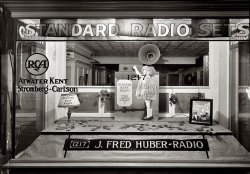 "J. Fred Huber Radio window," 1217 H Street NW in Washington circa 1926. "Phone FRanklin 36." View full size. National Photo Company glass negative.
Farking not requiredIf I didn't know better, I'd say that the display in the very center had been pre-Farked.

Atwater Kent Model 35"What could be simpler?" applies to to the Atwater Kent Model 35, which featured a single knob for tuning back when the majority of radios had three. The Model 35 sold for $65 less batteries, speaker and tubes.
J. Fred HuberHuber first opened shop on 1222 G street in 1925, moving to 1217 H street sometime during the summer of 1926.

Washington Post, Nov 22, 1925

Huber Opens New Studio
Announcement was made yesterday of the opening of a new radio studio by J. Fred Huber, until recently manager of the radio department of Lansburgh &amp; Bro.  Mr. Huber will conduct his studio in the store of McHugh &amp; Lawson, 1222 G street northwest, and will handle radio sets and accessories featuring Radio Corporation of America and Atwater-Kent products.
Previous in his last employment, Mr. Huber was superintendent of operations in the United States engineers and quartermaster departments of the army, and later in engineering practice on the Panama canal.  At one time he was wire chief for the local telephone company.  Assisting Mr. Huber in the conduct of the radio department will be E.G. Machamer, a former department manager for John Wanamaker Co., and Ray A. Dunbar, who served during the world war as a radio ensign in the navy.

I am going to have nightmaresabout that girl. Creepy. No neck. 
Dumb &#039;ol babyThey had to superimpose J. Fred's face onto that poor kids body.  No kid has ever been that ugly.  And you should have seen my brother!
Tin CeilingLove the old tin ceiling in the background.   Surprisingly, those have made a comeback in recent years.
(The Gallery, D.C., Natl Photo, Stores & Markets)