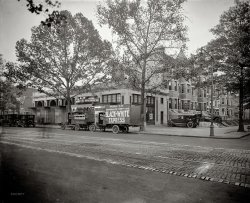 Washington, D.C., circa 1926. "I.C. Barber Motor Co., 14th &amp; Irving Streets N.W." Here we have everything from a Hudson-Essex car dealership to moving vans to a florist to "scalp specials." And not only ghost pedestrians in this time exposure but a ghost car! Also note the use of trees as 1 Hour Parking signposts. National Photo Company Collection glass negative, Library of Congress. View full size.
The CarI love that car in the parking lot... I can't tell what make it is, but it is sure classy.
[It's a brand-new Hudson. - Dave]
Aunt Polly&#039;s EssexAnd here I was hoping to catch a glimpse of a 1926 Essex again. My "Aunt Polly" (a friend of my grandmother's) had a 1926 Essex she bought new in Portsmouth, Virginia. I remember as a kid in the early 1970s riding in that car, with its acetylene headlamps and rumble seat. She had it until she died, in the mid 1980s. I don't know what happened to it after that.
And you don't have to be particularly old to know Glenn Miller's Pennsylvania 6-5-Oh-Oh-Oh, as I'm only 42.
SHorpy-633It seems we may have caught another historical transition here at Shorpy's - the phone system moving from 5 to 6 digit dialing in DC. Note the phone number of Black and White moving is COlumbia - 633 whereas the phone number of Story &amp; Co real estate appears to be FRank - 4100. When I was a kid I remember we were taught our phone numbers as the exchange followed by numbers. Mine was MUrray 4-6176. Anyone recall the most famous phone number of all... PEnnsylvania 6-5000?
PEnnsylvania 6-5000I sure do, and it's still the phone number at Hotel Pennsylvania in NY. Glenn Miller may have written the best advertising jingle of all time, and I don't think the hotel paid a dime!
http://www.hotelpenn.com/contactus.html
Say it With FlowersThe Gude Bros Co., established 1889 by Adolph and William Gude, is still in the wholesale floral business.  An early history and photos of the company. Adolph, a pilot, had an  airstrip built adjacent to their plant nursery in Rockville.
Old Phone NumbersThis is an absolutely GREAT street scene photo of the times in DC. And speaking of phone numbers, my family went from "2943" in Newburgh NY in the 1930s to "4-8168" in Wilmington DE in the 1940's, which evolved into "OLymp1a4-8168" into the early 60's, before it went all-numerical to 302-654-8168 by 1965. Just before that, I had moved to NY City, where they still were using those great old neighborhood exchange names such as as ALgonquin (in Greenwich Village), MUrrayHill (in East Midtown), PEnnsylvania (in West Midtown) and BUtterfield (in the Upper East Side). (Sigh...those were the days, my friends...) 
1926 Essex Here's one...

I.C. Barber Motor Co.According to Hudson-Essex ads in the Washington Post, the I.C. Barber Motor Company was at 3101 14th St N.W. Irving C. Barber made his name racing autos at the Benning track.  He won in 1915 and 1916 in his homemade bright red "Eye-See-Bee" and again in 1917 in a "Beaver Bullet."
Hudson-EssexThe new-looking phaeton to the right of the dealership is neither a Hudson nor an Essex. It looks like an Oldsmobile.
All Hail the Hudson!By virtue of its ubiquity upon these pages as well as its exemplary ability to elicit extensive commentary, I hereby nominate the HUDSON to be the Official Automobile of the Shorpy 100-Year-Old Photo Blog. The fact that three separate examples of this marque owned by members of my family figure in a number of photos I have personally submitted should in no way be interpreted as bias on my part.
1361 Irving Street NWThe only structure here still standing is the apartment building that is now the Irving Station Condominium, at 1361 Irving Street NW, directly behind the lamppost. All the rowhouses from there to the corner have been demolished, and it no longer has the metal awning that is (barely) visible. On the site today is one of the entrances to the Columbia Heights Metrorail Station, and the Victory Heights senior housing building, with Irving Station still there. Great photo, fascinating material!
Gude FloristsThe Gudes also had a facility just south of Laurel, Maryland, where Laurel Lakes Shopping Center is now. For years there was a rose bush right alongside Route 1 at a dip in the road, where it was doused with salt-laced slush every winter.  A real survivor!  It still breaks my heart that I wasn't able to rescue it, or at least take cuttings, before it was bulldozed away for the shopping center.
Just north of the shopping center is a large public park operated by the city of Laurel, called Gude Park.
The OldsmobileThe car parked in the drive is a circa 1920 Oldsmobile.
I cannot find any pictures of Hudson's or Essex's with the canted hood louvers depicted.
Shown below is a 1919 Oldsmobile Model 37A that is almost exactly the same as the Shorpy picture, but the top is down.
Of further interest is the lock on the spare tire, the wood block acting as an emergency brake, and several notes/cards placed on the Oldsmobile that do not appear to be clear enough to read in the photo.
(The Gallery, Cars, Trucks, Buses, D.C., Natl Photo)