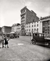 Washington, D.C., circa 1928. "Barrister Building, F Street N.W." National Photo Company Collection glass negative. View full size.
Oh Henry!The Kids got a box of Oh Henry! bars. A whole box, he must be rich! Or he's selling them.
[Or it's his pencil box. - Dave]
I hadn't thought of that one, probably correct since they seem to be coming from or going to School.
Etched in stoneNo adjustable rates mortgages at the Washington Permanent Building Association - 6 percent cast in stone.  Lots of patent lawyers and the ever-present cigar store, too.
QualityNice to see a Sign Shop that prides itself on workmanship. I see Jerry has opened his Restaurant up!
Barrister BuildingInfo on the Barrister Building at Shorpy Post: Slush Hour: 1916.
October 1970 (+42), Historical American Building Survey.



Date QuestionHow firm is that 1928 date? All of the cars I can see have an angularity - especially the flat tops of the fenders - that looks more like the late teens/early Twenties. Of course, they could all just be older cars.
[There are mid to late 1920s cars here, with 1928 District of Columbia license plates. Another clue is balloon tires and the number of cars with disc wheels. - Dave]
The littlest flapperThe youngsters very nicely and expensively dressed!  The little girl's outfit, with the cloche hat and knee-length coat and fur perfectly copies in scale those worn by the adult flappers of the day!
In the backgroundThere is Smithsonian American Art Museum on the backstage.
Modern view of the place
[At the time, it was the Old Patent Office. - Dave]
Six Per Cent Building The similarity of the Barrister Building and the Washington Permanent Building Association is more than coincidental: both were designed by architect Appleton P. Clark, Jr.



Washington Post, May 11, 1907 


M'Gowan Building Sold
Washington Loan and Trust Dispose of Property for $26,000.

The McGowan building, at 629 F street northwest was recently sold to the Washington Six Per Cent Building Association by the Washington Loan and Trust Company through the firm of Stone &amp; Fairfax.  It is understood that the price paid was $26,000.  The Six Per Cent Building Association moved into the McGowan building not long ago under a lease.
The property has frontage of twenty-six feet seven inches on F street, and its 120 feet deep, running back to an alley. For many years the Washington Six Per Cent Building Association occupied offices in the Second National Bank on Seventh street.  It recently left those quarters to make room for the growing business of the bank. The building association is one of the oldest concerns of its kind in the city.
It is thought that the building of the new union station will increase demand for property around Seventh and F streets.  Stone &amp; Fairfax have recently sold several buildings in this square.




Washington Post, Aug 25 1912 

The Washington Six Per Cent Building Association, to erect an office building at 629 F street northwest. A.P. Clarke, jr., architect, Melton Construction Company, builders. Cost $23,500.




Washington Post, Apr 14, 1931 


Capital Building Body 50 Years Old
Small Group Here Organized Permanent Association in Early Part of 1881.
By Thomas M. Cahell.
The Washington Permanent Building Association is now 50 years old.  Early in 1881 a small group of men met at Gustave Hartig's hardware store at Seventh and K streets northwest to discuss the formation of a building association, different from any then in operation in the District, in that  it was to follow the permanent rather than serial plan.
The permanent plan meant the continuation of business from year to year, instead of a series of periodical settlements as a serial association then operated. The permanent plan was adopted from Philadelphia, where all necessary information was obtained.
After a few conferences at the Hartig store, a larger meeting was held at Dismer's Saengerbund Hall, where preliminaries for drafting a constitution were settled. On May 14 the first meeting of the association convened at German Hall, on Eleventh street, between F and G streets northwest.
…
The association's first office was above the German-American National Bank, at Seventh and F streets northwest, where Hecht's store now stands.  In 1884 it occupied half of the first floor of the Pacific Building, now a part of the Hecht's store.  Office hours were then from 3 to 5 p.m. In 1898 it moved to the Second National Bank Building, at 509 Seventh street northwest, occupying half of that building until March, 1907, when it acquired its first home, the McGowan Building at 629 F street northwest.  At this time the minutes of the association were changed from German to English.  In 1913 the association's building was razed for its present modern banking office on the site, its temporary headquarters being at 631 F street northwest during the construction period.

Waiting for Il Duce.I expect it's just my fevered imagination but the balcony shown below just looks as if it's waiting for a suitable dictator to address the adoring masses. 
+88Below is the same view from May of 2016.
(The Gallery, Cars, Trucks, Buses, D.C., Kids, Natl Photo)