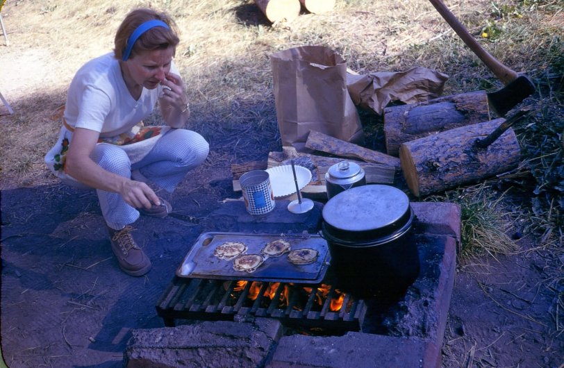 We're on a camping trip, late 1960s, I think. Not exactly sure of where we were.  Here's my intrepid mother, who is still with us and fully engaged at 92.
The hotcakes look a bit doubtful, as does she. 
In later years, she told me that these trips were not really a vacation for her. She did the same stuff on the road as she did at home!
Mom was (and is) such a good sport.
