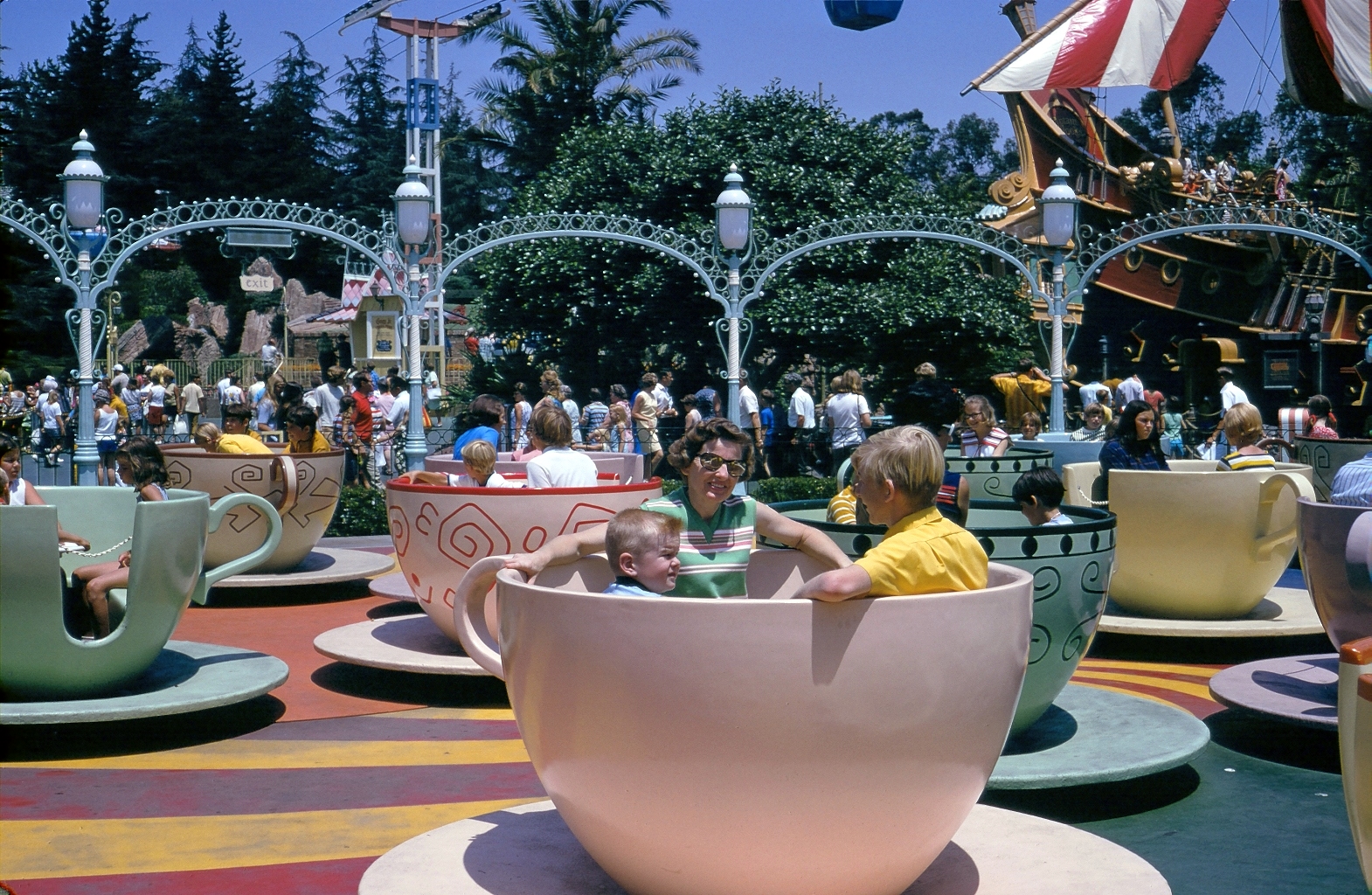 Disneyland about 1967. The "vomit cups," as I recall them. Here are my indefatigable mom, still alive and kicking, my little brother and moi. These were the days of the ticket books. The letter coded rides! From what someone told me, it is now nearly $80 to be admitted to Disneyland. Kinda makes me NOT want to go. This was one of a series of my dad's crystal clear 35mm slides. Dad was a fine amateur photographer. He just had a nice touch! Of course, depending on where he sent his film to be developed, results could vary.  Here's a link from a popular Disneyland site showing how the ride has changed over the years. View full size.
