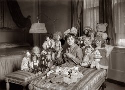 "Miss Smith and Dolls." Emily Smith (1901-1980), daughter of New York Gov. Al Smith, circa 1919-21. View full size. George Grantham Bain Collection.
The dolls eyesOk cute picture, cute kid, nice room, BUT look at that dolls eyes, curly hair with bow, standing on the bench, eyes to the side, has murder on her mind!!!! 
A pants suit in 1915?Doesn't it seem odd that the doll closest to Miss Smith, sitting on the bench to her right, is wearing what appears to be a colorful pants suit? Is it supposed to be a male doll with long hair, or maybe a foreign doll? I was under the impression that as close to pants as a female would come in that time period was maybe puffy bloomers for the most daring, but I'm no expert.
pant suitThe doll in the pant suit is a boudoir doll, popular among flappers in the 20s and 30s. It was designed for women, not children.
The dollIt's a circus costume. Ringmaster or lion tamer maybe? Pierrot style, like the clown at far left. Miss Smith looks like she could be 20. She seems to have a wedding ring.
Doll HouseEverything about this picture is CREEPY.
Knitting needles - or personal safety devices?Miss Smith can defend herself with those knitting needles, should any of her doll "friends" get out of line!
Miss Smith could pass for aMiss Smith could pass for a doll with a curly wig and a crochet hat and shawl. 
I have to agree that the photo is a little creepy though... 
Looks to me like somebodyLooks to me like somebody had money to have that many dolls back then.
The &quot;wedding ring&quot;The "wedding ring" is yarn.
[Something tells me you're looking at the wrong hand. Explanatory illustration from our Graphics Department below. - Dave]

BenchThis is a little offbeat, but I LOVE that bench the dolls to the left are sitting on.
Miss Smith and DollsMiss Smith turns out to be Emily Smith (1901-1980), daughter of four-time New York governor Al Smith. Below, Emily in 1924. The doll photo was made around 1920.

(The Gallery, G.G. Bain, Kids)