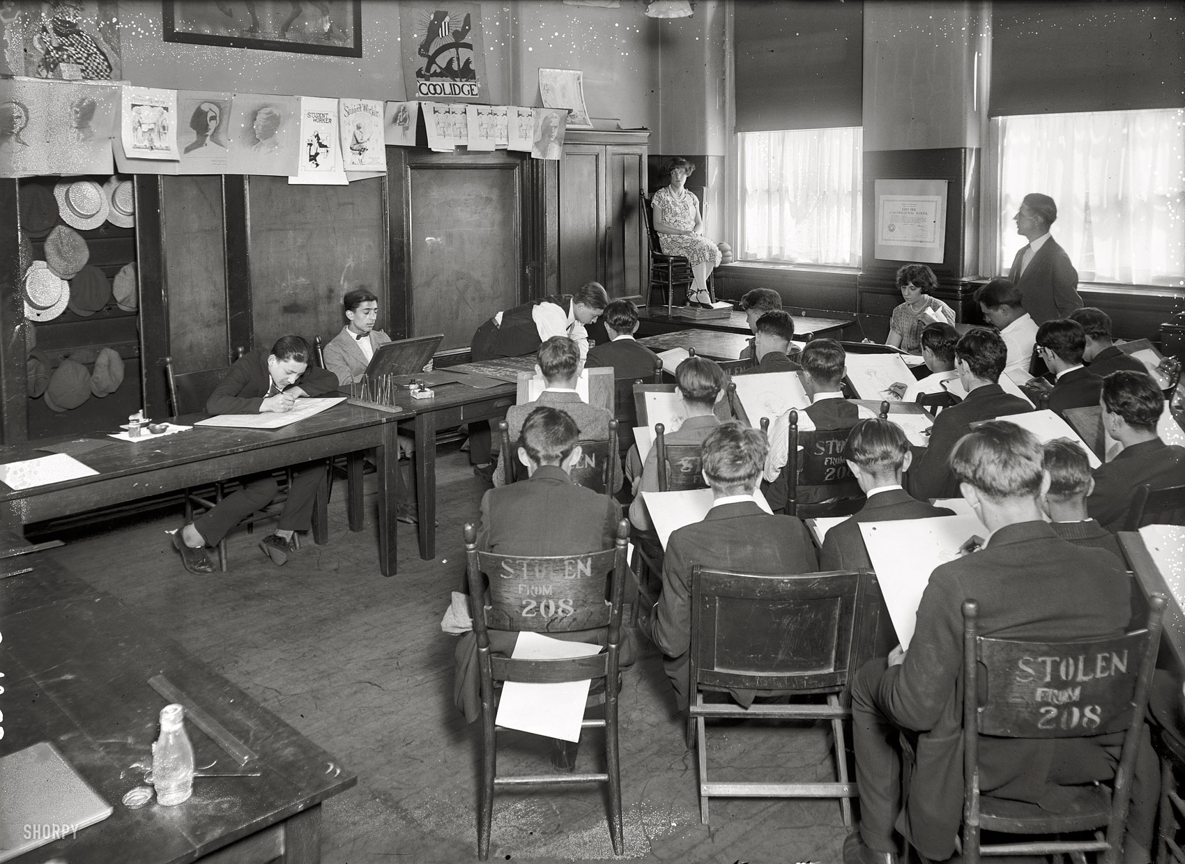 New York circa 1925. "Art Class (commercial)." The certificate or diploma on the wall bears the name of East Side Continuation School. View full size.