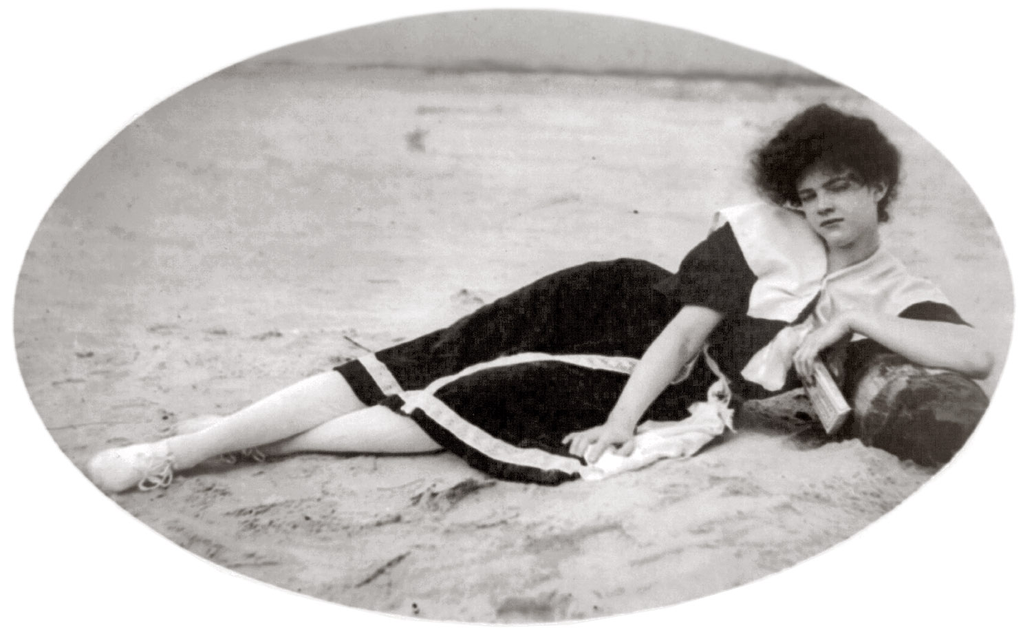 Woman in bathing suit lying on a unknown beach, sometime between 1910 and 1920. View full size.