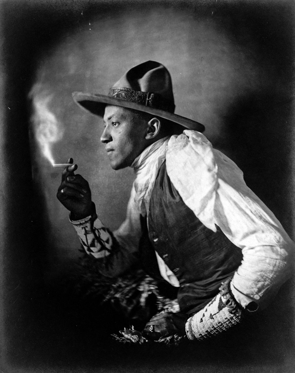 A portrait of a Sioux Indian smoking a cigarette. Photograph by John A. Johnson, c. 1908. View full size.