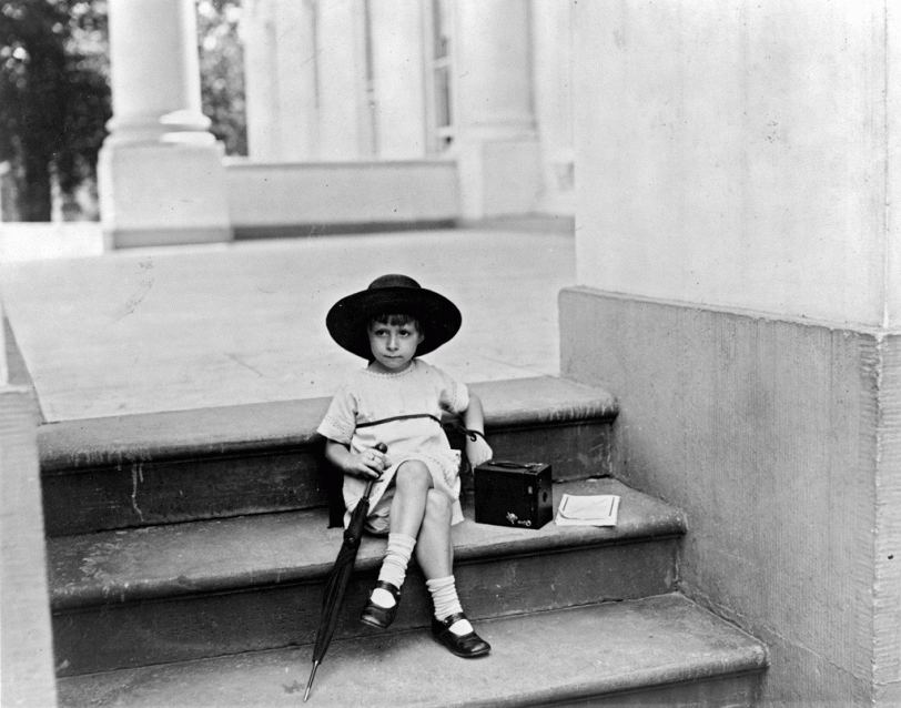 Little Miss Tarkington, the daughter of Mrs. W. Tarkington Jr., sits on the steps of the White House patiently waiting to snap a picture of President Warren G. Harding on June 29, 1922. From the National Photo Company collection. View full size.
