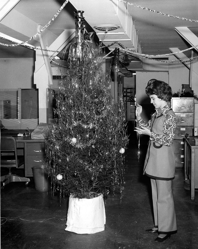 My mom decorates the accounting office Christmas tree at Ft. Stewart, Georgia in 1970. In another year, I would arrive. U.S. Army photo. View full size.