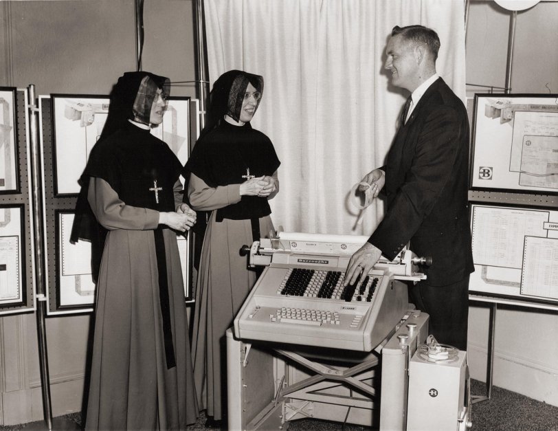 Dick Buckley, of Burroughs, explains the virtues of punched paper tape accounting machines to two Grey Nuns who are administrators of St. Joseph's Hospital in Lowell, Mass., circa 1963.
