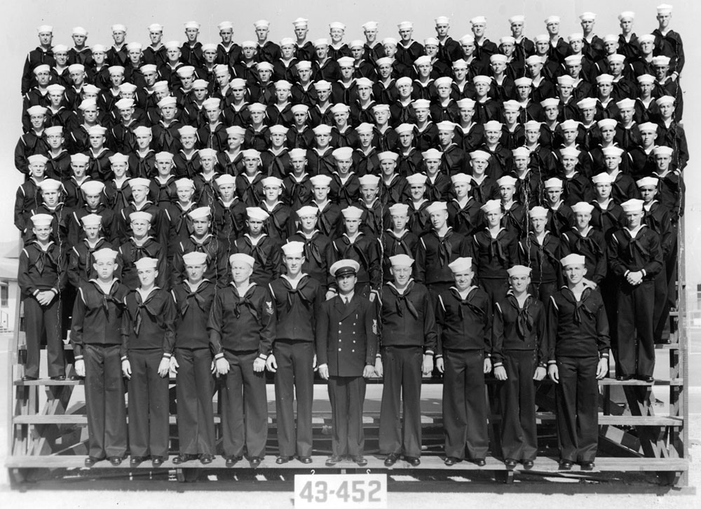 For context: My grandfather served aboard the YMS-299 in the Battle for Okinawa. I have several of his photos and am trying to figure out where they fit into his training/tour.

Is this a graduating class from boot camp, or a group he would have served with? Would it include the crew of his YMS, or would each of these men have gone into different assignments? How would someone try to get a list of names for a photo like this?

The back says:

"1943 after boot camp
San Diego, CA navy base
80 men to a platoon, with 2 platoons
160 men"

(NOTE: I only count 150 men, not including the officer.) View full size.