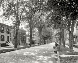 Ithaca, New York, circa 1900. "Greene Street." Hey, mister -- you missed a spot. 8x10 inch dry plate glass negative, Detroit Publishing Company. View full size.
No Electricity yet?I only see one wire, strung tree to tree, and nothing going to the houses. Was there no electricity or phones to the houses yet?
Broom ServiceBack when "street sweeper," like "computer," was an occupation and not a machine!
Hey, my home town!Thanks for this great photo. Let me point out that it's "Green," without the E. 
Alas, Alasfor the elm and chestnut trees of yore. How lovely they were. 
It seems those trees serve a dual purpose.   They have telephone wires strung on them. The first tree on the left seem to have a wooden sidepin with an insulator on it, and the next tree has the knob/spool type of insulator attached to it.
    The other purpose of course is to look beautiful in the fall.
Curbside to go    Are those steps at the curb for entering a carriage?
Dutch Elm DiseaseAre those the elm trees that died?
Keep up the good work Dave, these pictures make my day.
Playing HorseyWhat are the stacked blocks before the two houses in the center?  I guess they are to stand on to get up onto your horse (after it's been untied from the metal stand across the street).
[They're called mounting blocks (for mounting and dismounting a carriage) and hitching posts. - Dave]
What a beautiful neigborhoodSo sad to see the wasteland it turned into. (The same could be said for most of the American landscape.)
Half-bakedThe house in the foreground on the left is now a parking lot.  All the houses on the right have been plowed under for a modern bakery.
View Larger Map
No ParkingHow beautiful our streets were before we had to park cars all along them.
Time to SpareIn the distance comes a carriage.  Should be here in half an hour or so.  I'll go watch paint dry while I wait.
Mounting blocks!And the drone of leaf blowers nowhere to be heard. Where'd I put my time machine?
Somebody else&#039;s problemOne of my major "peeves" is that today's lawn service workers just take their leafblowers, blow the grass and leaf debris out into the street and it becomes somebody else's problem.  It also gets directed into the storm sewers and block up the drains causing sewer back-ups and all sorts of plumbing problems for the neighborhood.  Even though it is SUPPOSED to be against the law to do this, it is never enforced.  Not too much gets my goat, but leafblowers really DO.
Progress does not become this sceneThis makes me sad.  I looked at this scene, and said, "This is beautiful; I bet the only changes are that the street is now paved with concrete, the horse hitching posts are gone, and there are a few more wires strung through the air."
To see that one of the houses is a parking lot, and one entire side has been torn down for that THING on the right just makes me sad.  Yes, I realize this street may have become blighted 50 or 60 years after this picture, but it's just such a beautiful street here, it's such a shame.
Still a nice neighborhood"Wasteland"?? I explored around using the Street View posted below. It's still a very pleasant, leafy neighborhood with many if not most of the old houses still standing.
View Larger Map
This Old HouseI was certainly surprised to see that this was not just any generic Green Street, but the Green Street in my current city of residence! Yes, as others have pointed out, most of these old houses are gone, but Ithaca still has many, many old, historic homes similar to this. Unfortunately, few of them are single-family homes anymore-- they are mostly chopped up into two or three (or more) apartments. But such is the fate of a big old house in a college town.
Moonlight feels rightNo streetlamps!  I bet it was pretty dark along that street at night, with only the glow from the electric (or still gas) lamps from the windows of those gorgeous houses to light the way.
Still niceWandering about the neighborhood a hundred and ten years later, I'd still live there.  A hundred an ten years ago this was already a mature neighborhood, quality lasts.
Lots Still LeftWestern Upstate NY and else where around the Finger Lakes still has a lot of street scenes with all the houses like this still standing.
Take US20 East out of Buffalo and head to the NY State Fair. See a lot of rural people not effected by modern day life. Geneva, Batavia, Waterloo, Auburn. NY. Skaneateles could have been a set in a Hardy Boy book. Sits right on the North Shore of Lake Skaneateles.
In Toronto between Bloor and College St. same thing. Full of cars because of no driveways, but the houses are all still there. You can still time travel in your sub conscious  
I wish I could retire in the pastThe world of 110 years ago, while it lacked many good things we've learned and achieved since then, was very beautiful.
No driveways!THAT's what was bugging me about this picture--the lack of driveways cut into the curbs. You just don't see that now.
Let there be light!I was thinking the same thing as the person who wrote the "Moonlight feels right" comment but several moments later I did notice that there's at least one carbon arc streetlight in this picture.  It's hanging above the middle of the street above the street sweeper's left shoulder in the middle of the thick canopy of leaves, making it hard to see, but it's there.
What a shamethat beautiful things in life never stay the same.
Things have changed!How can something change like that? Beautiful photograph, horrible sensations now!
(The Gallery, DPC)