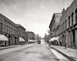 Marquette, Michigan, circa 1905. "Front Street." 8x10 inch dry plate glass negative, Detroit Publishing Company. View full size.
More Like 9 Cents!That "One Price Store" is no doubt akin to the "Two Price Store" we all went to: The Five &amp; Dime.
And who stole the Cent symbol from our keyboards?
Getz ClothiersIf I'm not mistaken, Getz Clothiers is still in the same building to this day - at least up until 2000, when I spent an eternity in Marquette one year.
One track townI would guess that this street was on a continuous loop of the trolley line, therefore the cars only ran one direction.
Early 99¢ Store concept?I wonder what that one price was? As a kid in the WWII years, I recall making many trips to the back of Menche's stationery store (in Forest Hills, NY) where two large glass cabinets were filled with a large variety of penny candy.
I wonder what the one price was here, and what it got you.
Vierling&#039;sThe young lad on the boardwalk is standing at the entrance to the Vierling's Saloon, which opened at that location in 1883. It is now called Vierling's Restaurant and Brew Pub.  On its website, Vierling's has several historical photos of the saloon interior. The restaurant has seating in the rear overlooking Lake Superior. The streetcar, moving east on Front, is at the intersection with Washington Street, Marquette's main drsg.
Getz&#039;s Getz's is still there.  In fact, I round the corner by Getz's everyday and hang a left at the top of the hill by the church (top of the photo) on my way home for lunch.   On a side note, a New Year's "ball drop" is performed from the top of the savings bank (building with the clock) -- it consists of a slow-moving, lighted tinfoil ball being lowered to the street with thousands celebrating. 
This is one of those pictures... that make me a little sad. It was such a gorgeous town. Google will take you to the same street, but a very different place. As noted below, Getz is still there. In the same building, too, so that's nice.
Unfortunately, the other places are pretty bad. I love that Shorpy's has put these here, however, so that we can see how incredibly beautiful they truly were!
View Larger Map
Unde FurI'd like to know the rest of the words "UNDE" and "FUR" on the partially obscured wall sign in the upper right.  "Undertaker" and "Furniture" seems like an odd combo.  "Underwear" and "Furrier?"  Nah, can't be.
PhotosJust to let you all know that although l do not comment very often l view this site at least twice a day, the photos are fantastic and is by far one of the best sites on the internet today. 
Thank you for letting me be able to view such fantastic old photos. it's like you are looking out of a window into a past time and you feel you could just walk into it.
Thank you all
Dean
Undergarments and FurnishingsIs my guess as to what the sign advertises.
Unde-FurIn frigid Michigan, fur underwear was a popular dry-goods category.
Up from the ashesMarquette was victim to many downtown fires that destroyed much of the beautiful brick and sandstone architecture from the 1850's through the 1930's.  I would urge and self-doubters to revisit what is happening in Marquette today.  As someone who is on the City's Planning Commission and working hard with others to restore and rebuild the classic architecture that once was, I would hope you would look twice at what we are doing.  In fact, we were just voted the National Preservation of Historic Trust's Distinctive Destination for Historic Places!  I love Marquette!
Empty streetOdd to see no horses or carriages or much of anything. Usually these old city street scenes were teeming with people, animals and vehicles.
&quot;Unde Fur&quot;It's Undertaker(s) or Undertaking &amp; Furniture;  the combo sounds odd today, but many undertakers did sell furniture &amp; even Victrolas !
 Here we go:
"Carl Tonella and John L. Johnason purchased the former Marquette Furniture Company owned by C.R. Brown and began operating out of a building on North Third Street which had been owned by Fritz Frei.
In 1894 with business thriving, they moved to a three story building on the corner of Front and Spring streets where they announced the addition of the undertaking business. "  (from: http://www.canalefuneral.com/_mgxroot/page_10728.php )
Unde &amp; FurMost likely, the sign said Undertakers and Furniture. Both were often in the same business.
Unde FurFor many years, it was common in small towns for the undertaker to also sell furniture. This was probably because the undertaker often made his own caskets.
The One Price StoreWas that the predecessor of the 99¢ stores? 
Marquette on the MarqueeAnatomy of a Murder - Great movie with ties to Marquette.  Hard to believe James Stewart, Lee Remick, George C. Scott, and Eve Arden were once there back in 1959.
(The Gallery, DPC, Streetcars)