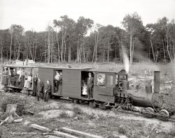 Harbor Springs, Michigan, circa 1906. "Excursion logging train." 8x10 inch dry plate glass negative, Detroit Publishing Company. View full size.
Unusual DriveI know next to nothing about steam trains (or any other type for that matter), but I've never seen a worm gear type set up to drive the wheels before. That's pretty interesting looking.
FrankenshayThe interesting thing about this Shay is that it doesn't have a base for the boiler to sit on. Don't think that I have ever seen one quite like this. Also of note is that the boiler sits back on the wheels instead of being over them or at the very least flush with them. Maybe the original was destroyed and the pieces for the drive shaft and such were fitted to whatever components they could find to make it work. Very much a backwoods sort of thing. The boiler probably comes from a totally different engine and was fitted for the purpose. Excellent find Shorpy! Anyone else have thoughts?
Shay loggerThis is a Shay geared logging locomotive.  What's unusual about this is that it's missing the shielding that you usually see around both the 3 cylinders and the gears that drive the wheels. The cab looks home-made, too, and you can see evidence of some significant damage around the steam dome (where the pipe comes out to the cylinders). At best, this is a loco that was substantially damaged and repaired.  But I'm wondering if it's a new boiler on a recovered Shay drive mechanism, a real kitbash.
Happy BunchThere seems to be a larger percentage of smiles in this photo than there are in other photos from this time.  Must have been something in that Michigan air.
Where&#039;s My HeadlightThat is a Shay locomotive, very common in period logging operations.  What set it apart is the gear drive vs. the side rods on typical steam engines.  Shays had the ability to climb very steep grades.  I notice also that the trucks (wheel sets) on the cars are not sprung.  I bet these folks were more than happy to stand at the end of their journey.
The Reverend Ms. Who?I'm intrigued by the woman wearing clerical collar and cross. She must have been from a very forward-thinking denomination to have been an ordained clergyperson in 1906.
United Methodist ChurchThe Rev. Ms. Who probably has something to do with the Bay View Association. These are what we call Summer People, and if you live in Harbor Springs that can be a derogatory term.  In 2010, Summer People would have nothing to do with religion.
2Shayhttp://www.shaylocomotives.com
A surviving Shay with a great deal of similarity:

LowriderI am not a train expert but after reading the comments on the engine and looking at the strange way the cars are attached to the trucks, I would say this train has been modified for a height clearance. The cars have a home made look to them and are barely tall enough to stand in. The roof line of the cars, the engine and the smoke stack are all the same. 
TrucksI think the trucks on those cars trailing the locomotive are the same design that are currently in use on the Eurostar trains.  Yep, quite sure.
Hemlock Central RailroadYes, this is indeed a Shay locomotive, and the reason it looks cobbled together is because it was--by Ephraim Shay himself, built in his garage.
Ephraim Shay invented and patented the Shay locomotive, which was exclusively built for the commercial market by Lima Locomotive Works, Lima OH, starting in the late 1870's.  The Shay was primarily used in lumber operations, including Shay's personal logging railroad the Hemlock Central, which ran excursions like this out of Harbor Springs during the summer months to supplement the logging revenue.
Shay built his three Hemlock Central Shays himself in his garage.  I want to say this is #3, but I can't be sure because I don't have my father's definitive book on Shays at hand.
The Hemlock Central was torn up in 1912.  Shay died a few years later.  He was a fascinating man, one of America's greatest inventors, holding many patents besides that on his geared locomotive.
Built by Shay HimselfAccording to the Shay historical site whose link is given below, those trucks are from a 9 ton Shay built by Ephraim Shay himself. He was from Harbor Springs and owned the two-foot six inch gauge Harbor Springs Ry., also known as the Hemlock Central. Vacationers were hauled for 25 cents a trip. Now the remaining mystery is: what was carried in that lock box on the side of the cab?
http://www.shaylocomotives.com/shaypages/EphraimShay.htm
Ephraim&#039;s OwnEphraim Shay, who developed the geared locomotive along with the Lima Locomotive works, lived in Harbor Springs and designed a hexagonal house with walls of stamped steel, built around a central tower.  The house still stands on East Main Street.  He also designed and operated a private waterworks for the town.
The Harbor Springs Railway (nicknamed the "Hemlock Central"), another Ephraim Shay enterprise operating with Shay locomotives, hauled lumber and ran passenger excursions for 25 cents a head.
Hemlock Central RailroadTurns out this loco was owned by the inventor of the Shay, old Ephraim Shay himself. Track gauge was 30 inches. More here.
(Thanks to the experts over at Railroad-Line.com)
Ms. SecularThat isn't a clerical collar. It's simply a woman with a white shirtwaist under her black overdress who is wearing a cross.  
What&#039;s in a nameRecords in my collection show the name of the engine to be "Baby." It's the best photo I have seen of her.
William Crippen &amp; Mr. ShayMy 4-great grandfather, William Crippen, worked with Ephraim Shay on parts and design in his efforts to make his first geared locomotive in 1877. Crippen operated the Cadillac City Iron Works, but his little operation was unable to fill the demand of Shay's orders. Crippen was also busy designing his own engine which he received a patent for on Oct. 17, 1882. He only built a single finished locomotive of his own design before he passed away at the age of 59 in 1888. He is buried in Cadillac, Michigan.
For more information about the Crippen Geared Locomotive, visit: http://www.gearedsteam.com/other/crippen.htm 
(The Gallery, DPC, Mining, Railroads)
