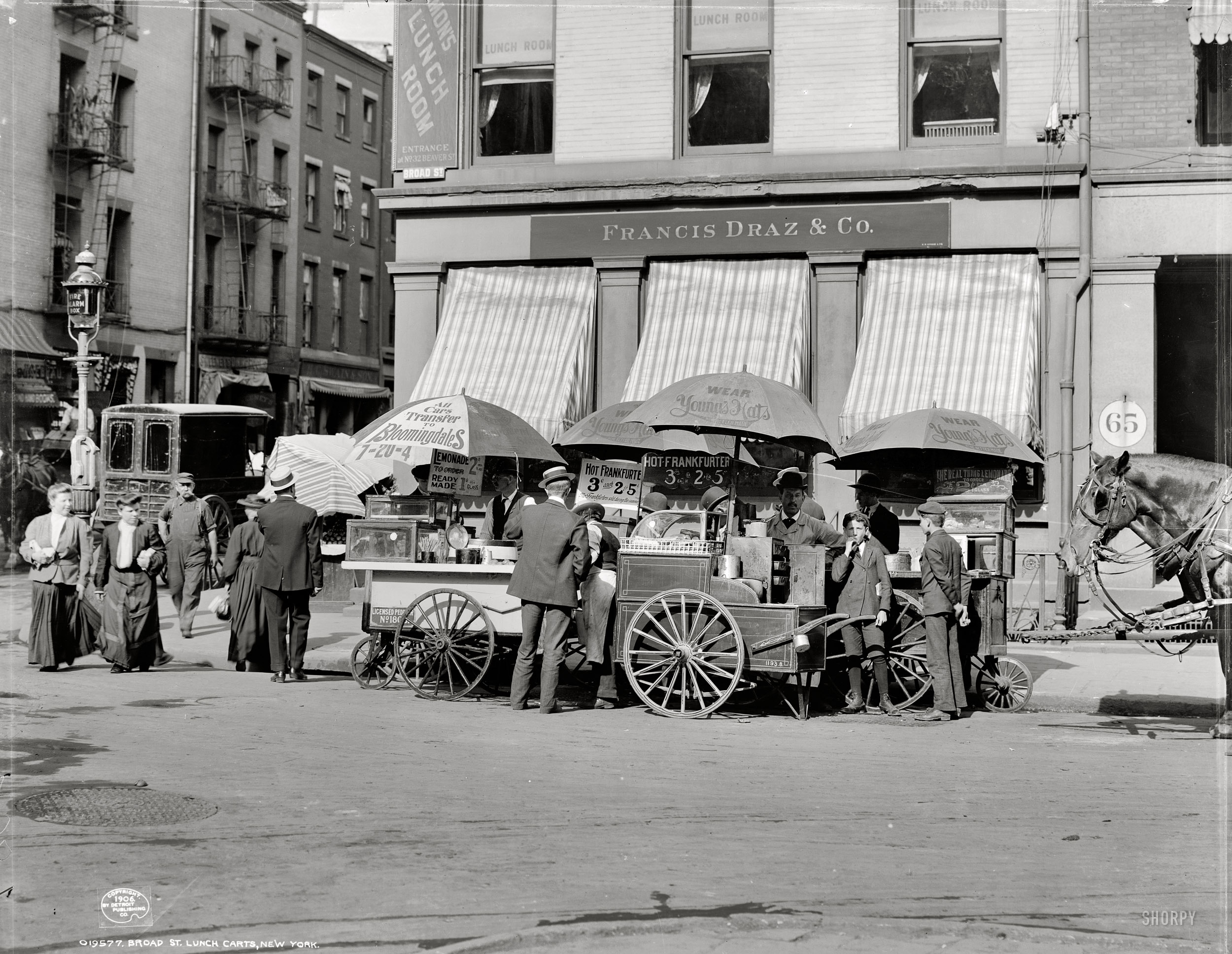 New York circa 1906. "Broad Street lunch carts." Hot dogs 3 cents each or two for a nickel; lemonade 1 and 2 cents a glass. Detroit Publishing Co. View full size.
