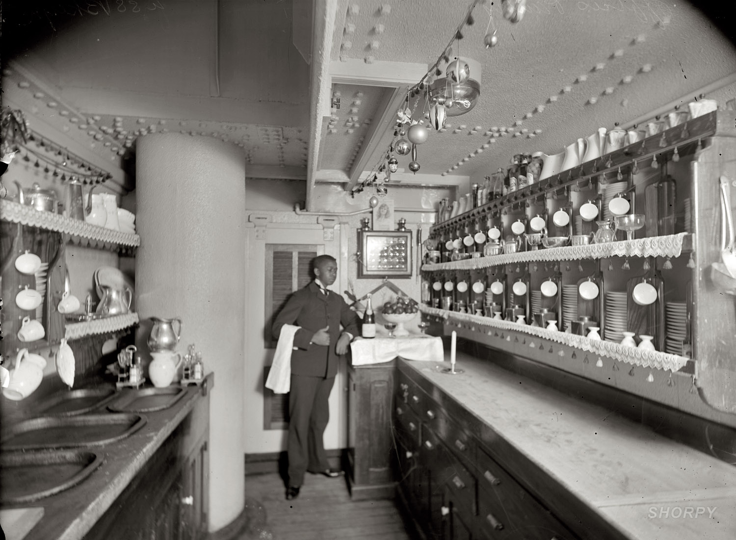Circa 1900. "U.S.S. Brooklyn wardroom pantry." Note the holiday decorations. The cruiser Brooklyn, commissioned in 1896, was a flagship in the Spanish-American War. Detroit Publishing Co. glass negative. View full size.