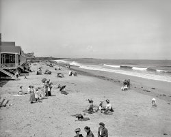 Massachusetts circa 1905. "Surf bathers, Nantasket Beach." Note the tall ships on the horizon. 8x10 inch glass negative, Detroit Publishing Co. View full size.
Can I, Mom?Every beach scene from this era that I've seen on this site quickly becomes my favorite.  I love that kid in the middle standing with his hands on his hips, as if semi-patiently waiting for the adults to stop talking so he can ask for something.  Permission?  Money?  It's a very accessible and timeless pose.  Love this photo!
Oh, DaveThis is Shorpy -- no need to tell people to look for details. There's at least an even money chance that someone will weigh in within the next 9 minutes with a learned disquisition on the schooner and its variants. 
Classy beach clothes!I'm always amazed at how immaculately everyone is dressed in these historical photos.  It really makes one think it was an unfortunate day the day they invented the T-shirt and cutoff jeans.
Paragon ParkNantasket Beach was the home of Paragon Park, one of the amusement parks established by the streetcar companies in this era to get people to ride all the way to the end of the line. You can see the roller coaster in the background. (Fun fact: roller coasters evolved from the same technology used for the streetcars!)  
Paragon Park is almost completely gone now, except for the carousel, which still operates.
Nantasket is now lined by a seawall which has replaced all these houses. It makes the beach incredibly narrow at high tide.
PurposeI don't quite get the purpose of going to the beach if all you plan to do is sit in the sand and sweat. Obviously neither swimming nor sun tans had been invented yet.
I love this photo.  It truly is a masterpiece and just a snapshot of life at the same time. Each group by themselves is interesting. The sailing ship in the distance, and the gaggle of young ladies just arriving to take their place in the sand. The clothing is amazing. So civilized. For whatever reason, this could be my all time favorite image seen on Shorpy. What a great era.
Red, White and PeelingThey may all be wearing hats and covered up with lots of clothes, but I don't think suntan lotion was invented yet.  I'd wager there were a fair amount of sunburned faces after a day at the beach. 
I have photos of my grandmother, mother and aunt all wearing pristine white zinc oxide on their noses in 1938 during at a day at Golden Gate Park.  Did they have something like that in use for preventing sunburns in 1905?  Of course, wearing a layer of thick white paste on your face kind of cuts into the fun as it makes you look like a clown.  We used to tease our red-headed cousin mercilessly when he wore it as recently as the 1960s.  He had GREAT self-esteem, though and logically informed us that it was HIS idea, not his Mom's and it was better than having a bright red nose later.  
Apres Midi sur la Grande PlageSo many smiles!
Why wear all those clothes at the beach?Because you have to wear all those clothes anyway - why not wear them where the sea breeze can cool you?
There's nothing more revivifying then sitting on one of the beaches fronting Massachusetts Bay, smelling the salt air, listening to the sussuration of the waves, and feeling that water-cooled air blowing over your skin. It sure beats sitting in one of those hot-box triple deckers in Dorchester or Boston and feeling the sweat pooling in the small of your back, listening to your children bicker and whine. To know that such relief was only a trolley ride away must have been immensely tempting, even to the heavily petticoated.
My grandmother could easily have been that little toddler in the photo. Her family loved day trips to the beach; it was part of the charm of living in Beantown. The photo looks almost as delightful as her reminiscences made it sound.
Searching the horizonFar right on the horizon there is a four-mast schooner. It was considered a big ship if there were more than three. Six was the most masts built and that was so rare that usually there was just one around at any given time. I have to say that the little I know about old sailing ships is what I have read since seeing this pic on Shorpy.
That water is c-c-c-coldCoppertone suntan lotion dates back to 1944.
But I don't think these people are sweating. I think it is a rather chilly day, which often happens at the beach.
Beach life as it should beNo tiny bathing suits you have to continually hold your stomach muscles in with, no speedos, no worries about guns and weapons at the beach.  Just a fun-filled, safe day!!  (so it seemed!!).  Great picture!  Looks very relaxing!
I&#039;ll be there soonI'll be heading there on Monday with my family.  Temps are supposed to be in the 90s,  I definitely won't be wearing a three-piece suit.
(The Gallery, DPC, Swimming)