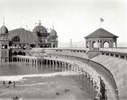 The Great Salt Lake circa 1900. "Saltair Pavilion." Our second look at this Utah landmark, a sort of Western, more wholesome version of Coney Island. 8x10 inch glass negative by William Henry Jackson, Detroit Publishing Co. View full size.
Saltair &amp; Carnival of SoulsSaltair was featured prominently in the famous mystery B-movie 'Carnival of Souls'.  That was filmed in 1962 when the place had fallen into a spooky abandoned disrepair.  
I hadn't seen that film when I attended a wild nocturnal party myself there, which I'll never forget.  A wild, crazy, spooky sort of place.
I think it all burned down in the '80s and was rebuilt as the water level of Salt Lake rose.
Saltair TodayThe original Saltair was destroyed by fire on April 22, 1925. All that exists of the original are the ruins of the power house and some piles out in the water.  Here's the latest incarnation.  Its used as a concert venue.
Largest Dancing Pavilion KnownContemporary accounts at the time report the Saltair Pavilion to be a church-sponsored venture constructed to offer wholesome entertainment. Portions of the establishment ran afoul of some Mormon's sensibility for serving alcohol.  The entire "sea-side" complex was reported to be one of the few Church business investments to lose money. 



Salt Lake City, Past and Present:
A narrative of its history and romance, its
 People and culture, its industry and commerce
1908 

In visiting the Great Salt Lake, which is reached by rail, about 15 miles west of Salt Lake City, the Saltair bathing and summer resort is the favorite place, which draws thousands of people daily during the summer season. Here the great pavilion is an attraction which has few parallels among the most noted resorts.
At Saltair is had a magnificent panoramic view of the famous Great Salt Lake with its islands, the thousands of bathers in the lake, the largest dancing pavilion known, and finally the grandest and most picturesque sunset ever seen. The magnitude and characteristic features of the construction of the Saltair pavilion may be comprehended from the following description: The pavilion was built by Salt Lake capital and Salt Lake workmen. Style of architecture, Moorish. Its construction commenced Feb. 1, 1893 and was completed June 1, 1893. Cost $350,000. Built on the waters of Great Salt Lake, 4,000 feet from shore, and resting on 2.500 10-inch piling.

Oh buoyI'm wondering, are the people in the foreground just sitting on the bottom, or are they, as you often see in the Dead Sea, floating buoyantly in the salt water?  And holy schmoley, is that guy wearing a straw boater in the water???
Tho it's extremely sad to think of this place burning, when I first looked at it, I thought of the many, many similar buildings across the country that were demolished when they outlived their usefulness.  The idea of a place like this getting smashed up is almost more painful to think about than fire.
Floater with the boaterMy favorite part of this beautiful photo.
Saltair MK1This was the first major incarnation of Saltair, built in 1893.  It burned down in 1925.  
The second Saltair was built and partially destroyed by fire in 1931.  It wqas rebuilt, but the lakeshore receeded leaving the place about a half mile from the water.  It closed during World War II.  After the war, most people did not want to make a 30 mile round trip for an evening's amusement. It closed for good in 1958.  Carnival of Souls was filmed there around 1962.  An arson fire totally destroyed the second Saltair in 1970.  Before it was destroyed, some of my friends and I visited the place.  It was a spooky labyrinth of falling-down buildings.  
The third version is a pale shadow of the originals.  It is a surplus aircraft hangar reassembled about a mile away from the old site. Just after it opened about 1980, the lake level rose and flooded it out for a couple of years.
It ain&#039;t very deepI am pretty sure the people sitting in the water Boater Man included have their bottoms on the bottom.  To their left is a kid standing only knee deep.
The lake covers approximately 1700 square miles, yet the mean depth is only 33 feet. On some beaches around Saltair it is not uncommon to stand 100 yards from shore and have the water only knee deep.  Depending on the amount of fresh water entering the lake the salinity can run from 5% to 27% averaging 16-20%.  I have been in the lake several times.  And once you get about waist deep, it very difficult to stand. Your body's bouyancy makes it almost impossible to sink.
Salt Lake City Soda Water Co.Back in 1970, when the remains of the Pavilion were still standing, we walked around under the deck among the pillars. These salt-soaked pillars had exploded from the crystallizing salt when they dried. I found a "Salt Lake City Soda Water" bottle and filled it with salt crystals from a nearby pond. I figured that if I found a cent, it would be corroded blue-green and sure enough, as I saw a greenish blob in the sand, I broke off the corrosion from the sides and had a cent. There was no recognizable features left except the bump where Lincoln's head was. 
(The Gallery, DPC, Swimming, W.H. Jackson)