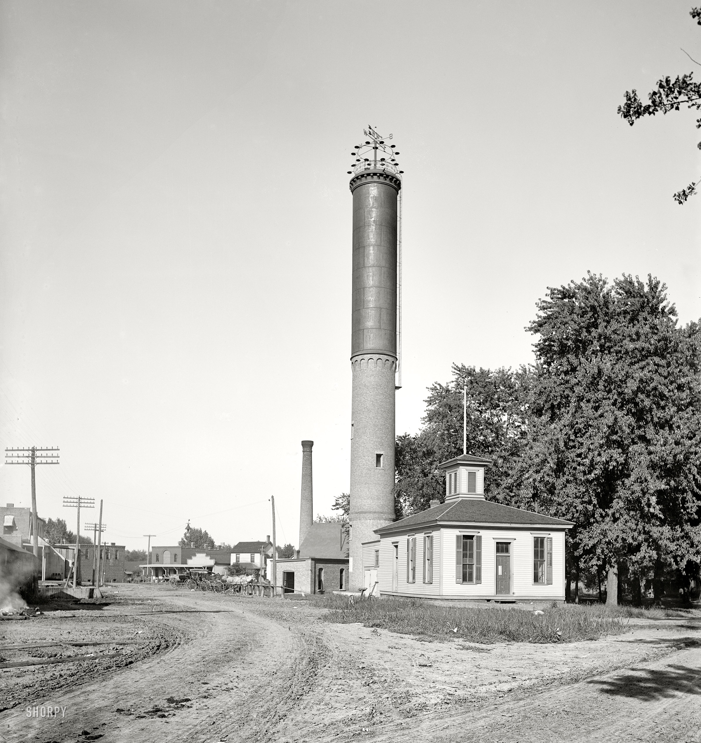 Circa 1900. "Water tower in Dwight, Illinois." Unusual columnar design with a brick base, topped off by a weather vane and lights -- a sort of smokestack-lighthouse-watertower hybrid. Detroit Publishing glass negative. View full size.