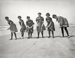 The Jersey Shore circa 1905. "A wringing match." Show us your knees! 8x10 inch dry plate glass negative, Detroit Publishing Company. View full size.
I say!Some very good looking young women here, especially the one with the stripey socks!
HappinessThis picture makes me smile!
Naughty, Bawdy Beach Beauties!They have that gleam in their eyes! Showing off a little leg and wanting to show a bit more! They are a cute bunch of young ladies having a good time and I love their spunkiness!
A peek of patellaWow, showing knees like that in 1905, those hussies! It's a good thing the Jersey Shore constables didn't see this, otherwise the gals would be hauled off for indecent exposure.
Where are they now with what goes on there?
No duplicatesHow many variations of the sailor suit bathing costume can you have?
Cheesecake FactoryI am shocked and appalled at yet another picture on Shorpy of young ladies in swimsuits. I was under the impression this is a family web site. Have you no respect for women? I just may cancel my membership. Or not.
And now for the Main Event!.Looks like an act in the "Wringling" Brothers Circus. 
Hey there!The tall girl on the right has a cute mischievous look on her face, and the girl second from left has the showgirl pose working. A nice December reminder of summertime!
UpstandingIt looks like the woman on the right would be head and shoulders taller than the others if she straightened up.
A Real BeautyThe girl on the right is a real beauty. There is a hint of a promise of something more in that look.
Scandalous!Wow! I have never seen such mischief makers on Shorpy from circa 1905. I love the expressions on their faces. The third one from the left's expression is saying, "You think this is something? Just you wait!"
Old NavyHave they really been in business that long?
PerfectPhotograph to help us all forget that the first snow of the season is just outside our door.  Hubba Hubba!
Saaaaaaayy!Those bathing suits aren't even wet.
Scamps!
Wow!I must say, I do believe I'm getting the vapors from such an erotic image!
And without showing any skin too!Stockings and bloomers under their bathing suits, and slippers of some kind. These girls may want to be naughty, but pulling up their skirts seems pretty tame.
Stay and playI wouldn't kick any of these ladies out of my sandbox for eating animal crackers.
I wonder about their shoesThey look like they are made of canvas. Were the shoes specially bought to go with the whole swimsuit ensemble, or was any old shoe good enough? To modern eyes, the only thing odder than shoes with a bathing suit are stockings with a bathing suit.
Bathing shoesBathing shoes were often worn, just as many people wear them these days at the beach partly for modesty's sake and partly for protection for the feet.
In the Victorian era, they were knee-length and were laced with ribbon. From the turn of the century until the 1920s, when women began wearing sandals to the beach, canvas was was the usual material for most beach shoes.
Surf slippersSwim shoes were still around in the 1930s. I wore them as a child as did most people whenever entering the surf because it was often very rocky.  Having said that, In the early 1900's I suspect "fully clothed" was the justification for shoes.
(The Gallery, DPC, Swimming)