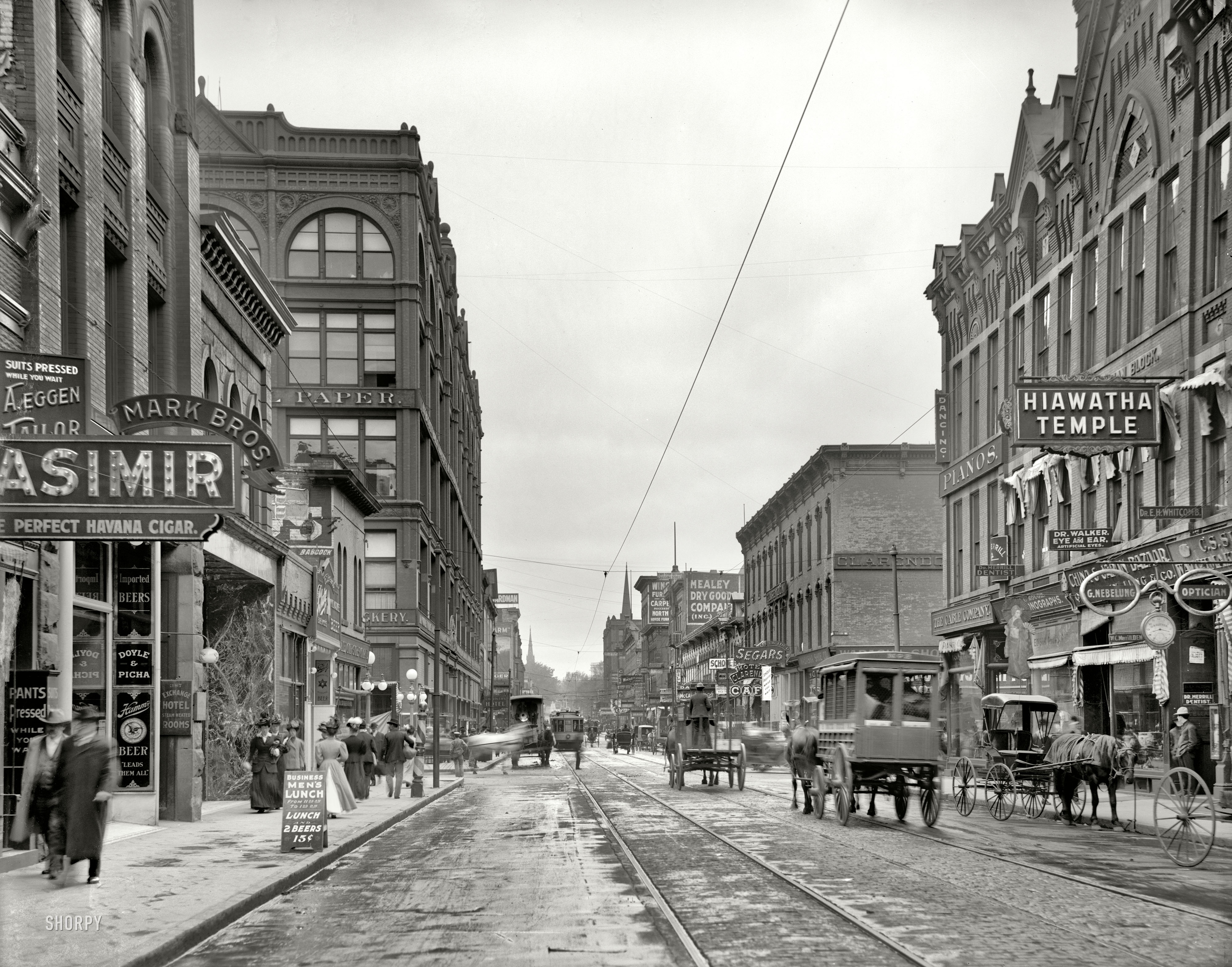St. Paul, Minnesota, circa 1908. "Wabasha Street." Abundantly equipped with the standbys that Shorpians will recognize as essential to a smoothly functioning business district: fraternal organization, painless dental parlors, purveyors of cigars and prosthetic eyeballs, optician-jeweler (with the 8:17 clock-sign) and, last but not least, "Business Men's Lunch (And 2 Beers)" for 15 cents. 8x10 inch glass negative. View full size.