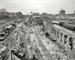 New York, 1908. "Excavations for N.Y. Central Station." Grand Central Terminal under construction, with Detroit Publishing's camera turned around from our previous view  of this monumental engineering project. View full size.
Mansard RoofI like the classic 19th Century Shaefer Brewery Works in the rear center...but what is the building rising out of the horizon on the left side?  It looks kind of spooky in an old hospital or orphanage kind of way. I'm assuming both buildings are long gone.
Mini PanamaSteam shovels, terraced excavation, dirt trains, concrete and steel. It's like a scaled down Pamana Canal, which was being dug at the same time this picture was taken.
FascinatingWhat really fascinates me about this photograph is that two eras are meeting head on. There are wooded platform passenger and freight cars, complete with turnbuckle truss rods and new electric motors in this photograph. There's wooden signal bridges (or at least I assume they're signal bridges) and the steel supports that still in use in Grand Central Terminal. The steamshovels are cutting edge, whereas the other work cars have wooden frames. What a great juxtaposition.
SteamedI know that by 1902 steam locomotives were banned from operating within the limits of New York City after a crash that same year caused an uproar.  Interesting then to see at least two in this photo.  I wonder if the New York Central Railroad got a special exemption for the construction of the terminal.
Schaeferwas the one beer to have when one had more than one!  Schaefer sold the lot on the east side of Park Avenue between 50th and 51st streets for $1.5 million to St. Bartholomew's in 1914.
Blowin&#039; in the windAmerican flags, laundry, and this wonderful flag over the Bible School. Anybody know what the address was?
Fireless cookersThe two locomotives observed in the terminal excavation by one poster were known as "fireless cookers." They used steam accumulators instead of boilers, with the steam coming from a stationary boiler. The locomotives themselves had no fires; you can see that they carry no coal.
Steamed Part 2I believe the 1902 ban on steam engines in NYC related to operation in tunnels. See  https://www.shorpy.com/node/1782 for an example of a steam engine operating on the streets of NYC in 1911. This photo is one of my favorites on Shorpy, showing a rich street life in the early 20th century.
S MotorsThe two electric locomotives are "S Motors" I think. They would have been only a couple of years old in 1908. Here's a picture of a survivor from the Illinois Railway Museum.
In the WindsThe Bible School flag flew atop home of Bible Teachers' Training School at 541 Lexington Avenue (49th Street).  
Steam Engines.In regards to the steam locomotives in this picture, it's more likely that they were classified as "Contractor" locomotives, and thus fell in with the permits that allowed steam engines (engine in as much powered by a boiler) like those in the cranes to operate in the city on a limited basis. 
It is worth noting that the actual "ban" back in 1902 was passed after a train struck another while in a tunnel.  The ban itself however did allow certain locomotives, such as the two shay types that the NYC operated along the port areas, as well as numerous small locomotives like these contractor engines, to continue to operate under certain conditions.  As stated above, in this case they would have fallen under a size restriction, being used in construction.  In the case of the shays, it was the fact that their top speed was barely 13 mph.  
(The Gallery, DPC, NYC, Railroads)