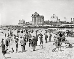 Atlantic City, New Jersey, circa 1908. "Hotel Traymore, bathers on the shore." 8x10 inch dry plate glass negative, Detroit Publishing Company. View full size.
Time Traveler Alert!The man directly behind "Freud" -- The Captain looking for Tennille.
Unrecorded TolkienHobbit throws stick for dog.
Razor&#039;s edge!The Gillette Razor sign in the background would fall over from the number of mega blades we have today!
POOF!No Snooki!
Where&#039;s the rest of me?Right behind the kid with the dog I see two legs and feet in wingtips sticking out of the sand, but no apparent torso or head. An early Sopranos reference?
Great Day for the BeachIt must be, or there wouldn't be such a big crowd.
Compared to today, it's odd how many of the people are wearing street clothes -- jacket and tie with starched Edwardian collars and brimmed hats for the men and ankle length full-cut dresses for women.  Bathing attire for men seems to be a T-shirt or tank top with tight fitting shorts (which would be acceptable even in most restaurants in Atlantic City today!)  Women seem to just have a shorter skirt for bathing -- must have been very clumsy in the surf line.
However, the lifeguards are well equipped.  Note the teenage boy in horizontally striped tank top on the left, leaning on a surf boat, lapstrake planked, with thole pins for the oars instead of metal locks.  This type of boat, rare today, is the ancestor of the powered "Jersey skiff" used in racing.  I think the rowing surfboat version seen in this photo was called the Sea Bright Skiff (after the northern NJ beach town of Sea Bright.)
M-BThe Marlborough-Blenheim hotel is also in this photo.  It's the structure with the beautiful dome and chimneys to the left of the Traymore.  It was once the largest reinforced concrete building in the world.
AnalysisSigmund Freud pauses for a pose whilst studying the peculiar humans reasons for returning to the sea. Standing directly behind Siggy is William Asher, inventor of the beach blanket.
Inevitable fat commentNot an obese person in sight. Imagine a similar cross section today.
AhhThere's nothing I enjoyed more as a boy than being serenaded by a barbershop quartet as I dug a hole in the wet Jersey sand. Thanks Dave-for the memories.
Clothing Optional?My eyes must be deceiving me. If this man is as naked as he looks, I believe he would be causing more of a commotion than what is evident.
[Eyes deceptive. Bad, bad eyes! - Dave]
Safety razorOh wow, I didn't realize that Gillette safety razor design went back so far. I have one of those razors in my medicine cabinet, although I haven't used it in a while. The last time I tried using it it sliced me up good compared to the latest plastic stuff. I guess safety is a comparative term.
Doncha wonderwhen the first shirt came off on the jersey shore?
My grandpa on the beach"Freud" looks exactly like my paternal grandfather, who always dressed with a wing collar. The daytime collar was smaller than the nighttime collar. As time went by my grandmother had a lot of trouble trying to find the right size or at least what Grandpa said was the right size. 
(The Gallery, Atlantic City, DPC, Swimming)