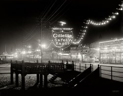 Atlantic City, New Jersey, circa 1910. "The Boardwalk at night." 8x10 inch dry plate glass negative, Detroit Publishing Company. View full size.
The boardwalk at nightis really a timeless view.  One can almost see Snooki and Jwoww staggering along the boards in the harsh glow of the electric lights.  
No PeopleThat's really unusual for any photo from Atlantic City.
[That blur on the boardwalk is people. This was a time exposure. - Dave]
Return of HelmarYes! The Helmar Cigarettes sign at night! I loved the spare wire construction of it in the daytime shot and wondered about it. Now I see that it was apparently holding lights. One of many things I love about Shorpy is that the answer to questions usually shows up eventually-- either in another shot or from a commenter.
This is a gorgeous view though. I can't get enough of these black and white nighttime scenes.
Not a dirty Brady in the bunchFrom the 2000 Arcadia Publishing book Atlantic City by John T. Cunningham and Kenneth D. Cole:
When bathers in 1887 shed their exhibitions, they did so in bath houses such as Brady’s Baths. Each day bathers leased suits from Brady's for wading in the water. For those who abstained, Brady's built a covered observation deck just off the boardwalk. The woolen or flannel suits may have endangered bathers if they ventured too far into the water, as the suits became heavy when waterlogged.
["Shed their exhibitions"? Hm. - Dave]
Tripician&#039;s MacaroonsA few of the pictured businesses on the boardwalk:

C.M. Kuory (furniture).
The Tokio.
Field's Mexican Store.
Shourds.
 Tripician's (confections), still in business.

In old ACEven though I'm an avowed tv addict I don't like to apply ANYthing I see on the tube to my beloved Shorpy page. I like to keep you separate from the rest of my world, kinda like an oasis. Gotta make one exception though; doesn't look like I'm gonna be able to not think of "Boardwalk Empire" whenever I see vintage pictures of Atlantic City. They just made that era in that place so VIVID.
An Enduring ProductThis morning I "shaved by myself" with my old Gillette Safety Razor, a close relative of the one being hawked in this photo.  It's still a great shave. 
The Safety Razorshould never be used by five-year olds as a means of washing the remnants of a spaghetti dinner away ala "shaving just like Dad". The result may be a small scar on the upper lip like mine.
GhostelI love how the old Hotel Traymore is just barely visible in this shot. The floodlights on Brady's Baths gives this photo a remarkable feel.
Neon evangelism?I was always taught that we cannot shave ourselves; only Jesus shaves. Or something like that.
Miami-CareyOff the wall like most of my comments, but, here I go anyway. This reminded me of the old medicine chests with the slot in the back to dispose of your used razor blades. All they did is drop into the space between the wall studs. This was in the days of real men who didn't need no stinkin' insulation!
ShopfrontsFive wonderful shopfronts in the foreground, from F.W.Woolworth to The Tokio.  I grew up in Upminster, Essex, England and our local 'Woolworths' had a similar shop front to this one - although it was never known as the 5 and Dime, for obvious reasons.
Boardwalk EmpireI don't know about Snooki, but I can imagine Nucky in this picture.
Something went wrongJudging from the 'movement' in the lights, it looks like either somebody kicked the tripod during the exposure, or it wasn't completely steady. I can't imagine the razor was moving during the exposure.
[The camera moved near the start or end of the exposure. - Dave]
From the Movie &quot;Atlantic City&quot;Like Burt Lancaster said, "In those days, Atlantic City had floy-floy."
Safety razorI last used a safety razor a couple of years ago just to try it out for old times sake. I guess there must have been a trick to using one, because even with a new blade my neck was full of little nicks. Needless to say I went back to the more modern version.
(The Gallery, Atlantic City, DPC)