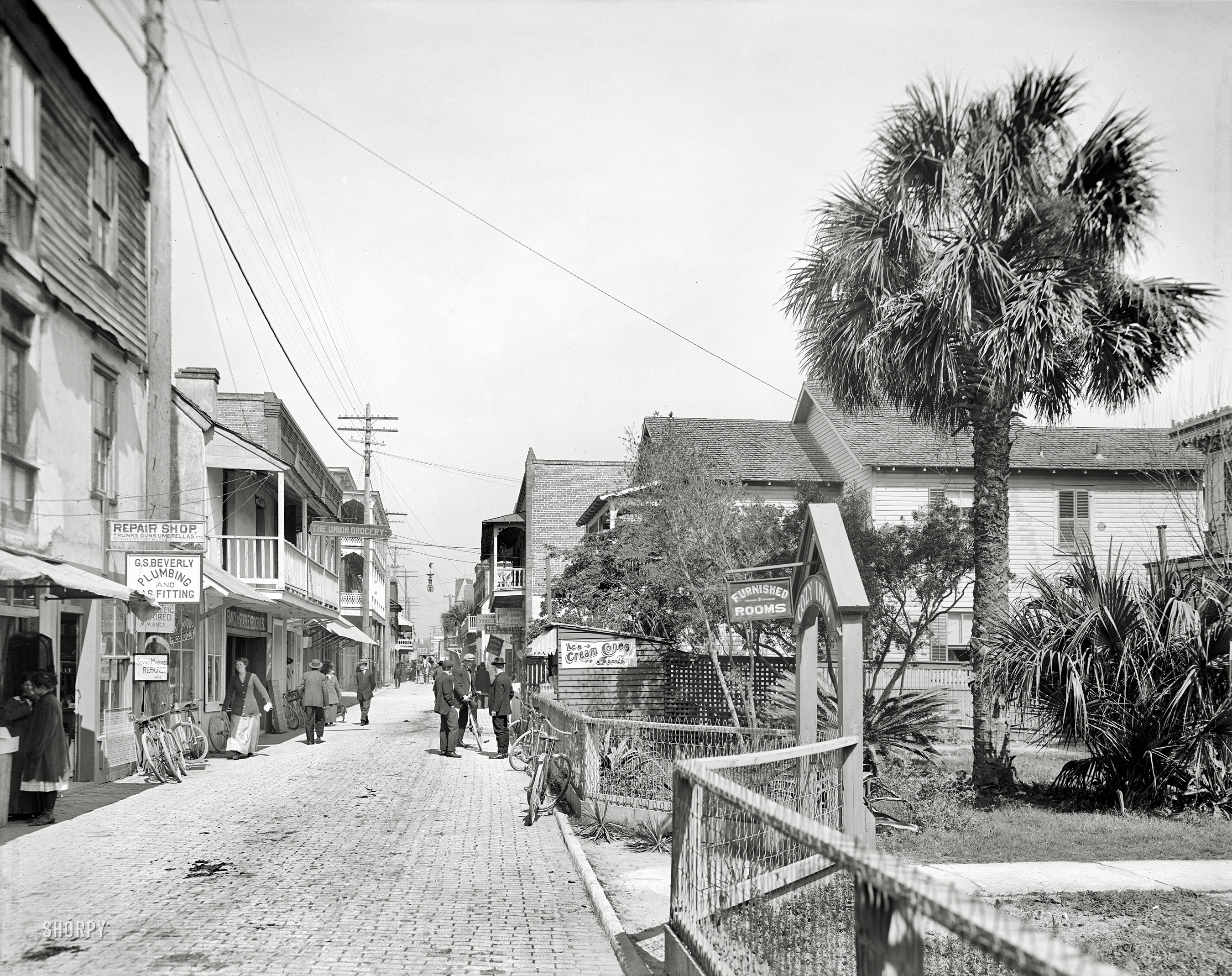 St. Augustine, Florida, circa 1908. "St. George Street." Where ice cream cones and gun-trunk-umbrella-sewing machine repairs are just a few steps apart. 8x10 inch dry plate glass negative, Detroit Publishing Company. View full size.