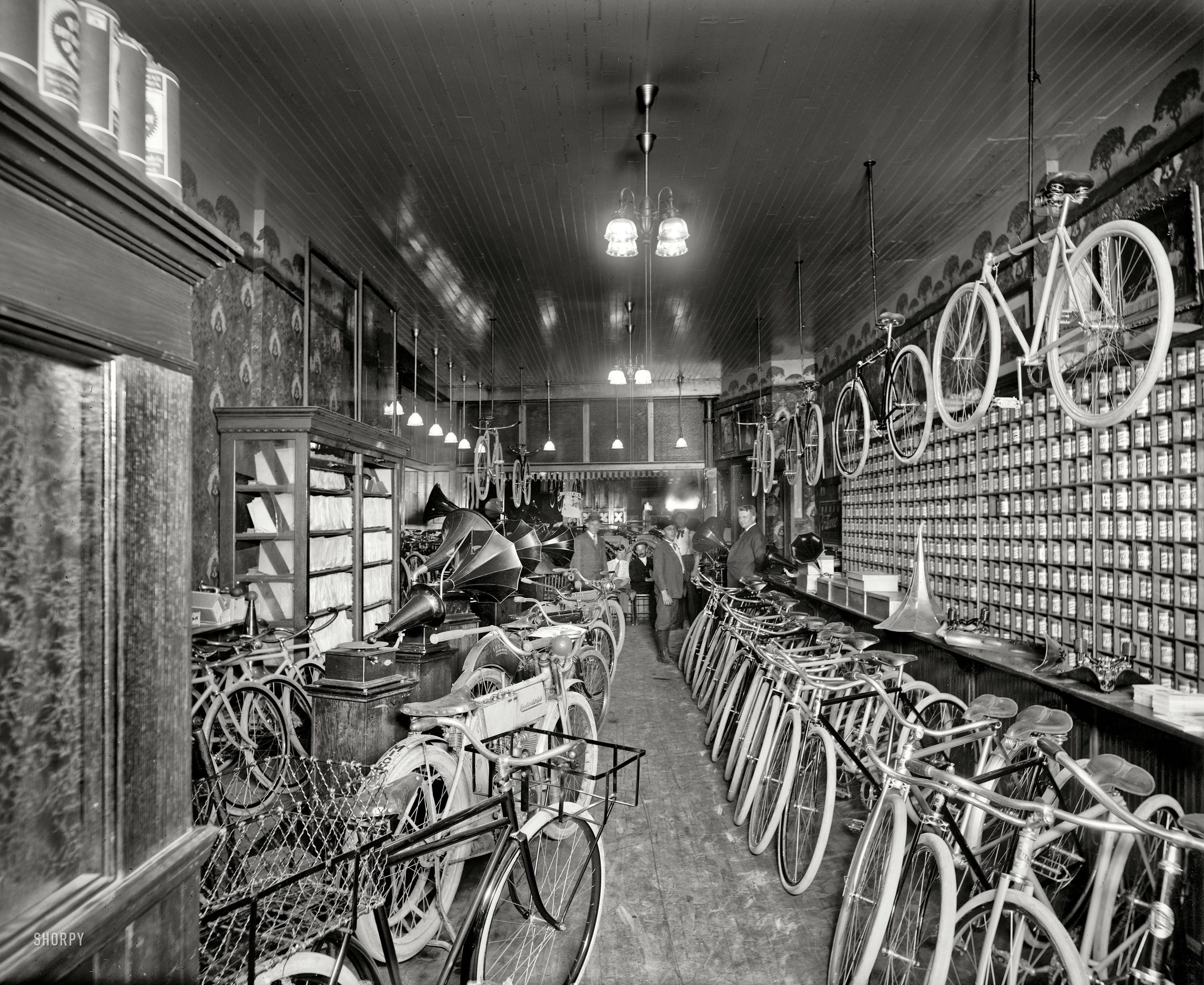 Detroit, Michigan, circa 1912. "Metzger bicycle shop. Detroit City Gas Co." This photo of a cycle (and phonograph) shop was taken to show off the gaslight fixtures. 8x10 glass negative, Detroit Publishing Company. View full size.