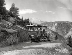 Colorado circa 1910. "Crystal Park autoroad trip. Pike's Peak and Cog Road from Inspiration Point, alt. 7945 feet." At the end of the road, a handy turntable. 8x10 inch dry plate glass negative, Detroit Publishing Company. View full size.
Now I get itMy mom has similar pictures from the Dakota Badlands, snapshots from the 1940s.  As I child, I could not understand what was so everlastingly fascinating about rocks and trees.
Walls of Paradise


The Packard, 1910. 


On Mountain Trails
Eight Thousand Feet Above Sea Level, Packard Trucks Fitted with Sight-Seeing Bodies Beat the Colorado Burros at Their Own Game 

To Crystal Park in the heart of the Rockies is the scenic trip advertised by the Crystal Park Company of Colorado Springs. Five Packard sight-seeing cars are used on the route, one leaving every hour from Manitou.
From Manitou to the Gateway of Crystal Park is a steady climb of 2248 feet. One mile of road covers thirty acres of ground, winding in loops across the face of the mountain, and in one place completing a double bow-knot.
To make possible this wonderful scenic trip, the company has built its own road up the mountain. This road is carved out of the solid rock and is as smooth a highway as you will find wherever your travels may lead.
On leaving Manitou the road leads straight to the mountains. Almost at once the tourist reaches a country as wild and rugged as any ever travelled by Zebulon M. Pike on his first famous visit to the Colorado Rockies.
…
Crystal Park itself was purchased from the estate of the late John Hay, Secretary of State under McKinley. It was in a log cabin in Crystal Park that Secretary Hay sought seclusion while writing his story of the life of Lincoln.
Until the advent of the Packards but few tourists have visited this beautiful natural playground in the heart of the Colorado hills.




Forest and Stream, Vol. 81, 1913.

I made up my mind to one thing, that it did not matter how often I visited Colorado Springs in the future. I would never attempt another trip by auto to Crystal Park, till the auto company that controls the road up the mountain had so thoroughly barricaded the sides of the road next to the walls of those deep gulches, and deeper ca&ntilde;ons so as to make it impossible for the auto to go off into one of them, either face foremost, backward, or sideways, no matter what happened to it. I have always had a great desire to be in an exceedingly calm state of mind when I am called to give an account to the Great Judge. I have no desire in the world to go by the way of an auto over a precipice 100 or 500 feet deep, or to be ushered out by means of a cyclone; hence my great caution.

-G.S. Wyatt.





Seeing the Far West, John Thomson Faris, 1920. 

Up one of the canyons reached from Manitou leads the Crystal Park auto road. By tremendous zigzags it climbs Sutherland Canyon, where Pike the explorer succeeded in outwitting pursuing Indians, up the rugged slope of Eagle Mountain, to a point under Cameron's Cone. Loops, hairpin turns, and a steel turntable help in the conquest of the mountain. The road affords views so different from those spread out before those who go to the summit of Pike's Peak that both trips are needed to complete the vision that waits for those who would persuade the Walls of Paradise to yield their secrets.

Crystal Park Auto TripsThe charabanc, or sightseeing bus, is a Packard truck from about 1910.  
Colorado did not issue license plates or register vehicles until 1913 so there are pre-state municipal license plates on the back of the bus.
I find the fact that someone actually built a turntable on a mountain very novel.  When I was young, I was shown an old garage in a very nice neighborhood that had a turntable inside.  This enabled the owner's wife to never need to back the car out of the driveway.
There is an excellent website with more photos of this road trip here:
http://historiccrystalpark.blogspot.com/search?q=turntable
(The Gallery, Cars, Trucks, Buses, Railroads, Travel & Vacation)