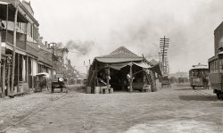 Circa 1880s-1890s. "The old French Market, New Orleans." Photo by William Henry Jackson. Detroit Publishing Co. glass negative. View full size.
Deutsche GroceryApparently the Old French Market had a "Deutsche (German) Grocery." Grocery is, of course, an English word; the German one would be Lebensmittelgeschäft. There must have been quite a number of German-speaking immigrants to make it beneficial use such a sign. 
High &amp; Dry GroceriesThe "Deutsche (German) Grocery" is north (roughly) across the street from the French Market; the French Market is that  irregular-shaped long  structure in the center of the photo.
Last time I was in New Orleans, 25 years ago, there was at least one long-established grocery store in about that same location.
The French Market is in the high ground area, such as it is,  of earliest New Orleans settlement, and probably didn't get flooded after Katrina, although I may be wrong about this.
---
Almost 50 years ago, I lived on the other side of Canal Street, about two blocks toward Lee Circle from the http://Liberty Theatre, www.shorpy.com/node/5786.  There was also a nearby second theatre; I remember going to both.
Shorpy, thanks for the memories!
Gaslight to Carbon ArcThe Southwestern Brush Electric Light and Power Company had these carbon arc streetlamps up and burning by the end of 1882. The street gas lamp pictured is about 40 years older. There were 400 electric streetlamps powered by 12 generating stations. These were the days of DC municipal power, supplied for streetlights only until Edison came to town in 1886 to provide power for indoor incandescent lamps. I am fascinated by the wires in these old photographs and the eventual "current war" between AC and DC: Westinghouse vs. Edison.
LocationI'm still trying to figure out exactly where this was, since the area around the French Market has changed a lot in the last 100 years or so. It looks like the street on the left is Gallatin, now French Market Place. The building at the very end of the street is the old U.S. Mint. The street on the right would be Peters, which ran along the river. 
Where it&#039;s at!I took a walk down to the French Market this morning and it looks like the photo was taken from the corner of Decatur and St. Phillip streets. Decatur is on the left (I wrongly identified it as Gallatin in an earlier post and that's not the US Mint at the end of the street) and Peters is on the right. Some of the buildings on Decatur are still there and you can line them up to figure out where the photographer was standing.
Love the French MarketI used to travel to New Orleans in the 1990s, and my employer at the time had a condo in the Quarter for out of town visitors. 
I spent a lot of time in the French Market (I didn't patronize the tourist trap bars or gift stores). The market was open 24 hours a day at that time. I brought home a lot of pecans and cajun spices, but passed on the alligator meat offered by one vendor.
French Market: Same but differentThis is just up from St. Philip Street, where Decatur &amp; N. Peters Streets split. The "Red Stores" building is at the right.
Seen is a part of the French Market that used to extend upriver a bit further.  There used to be several stalls beyond the Morning Call Cafe (now the location of "The Market Cafe" restaurant).  
In the Great Depression, the Works Progess Administration did lots of good works in New Orleans, paving streets, building parks and playgrounds, and renovating public buildings. From a historic preservation standpoint, however, the 1930s WPA work on the French Market was a mixed bag. They renovated some of the oldest structures, but also tore down several buildings that were already more than a century old at the time. 
The attached photo taken a short distance down and to the right from the William Henry Jackson photo shows WPA workers on North Peters on 5 January 1937; the Morning Call is to the left.
--Infrogmation of New Orleans
Ship&#039;s ChandleryTwo storefronts, one says "Grocery and Ship Chandlery" the other "Ship Chandlery," the latter phrase indicates they would provision ships with food.
In searching around I found that another grocery and ship's chandlery farther down the street (near the corner of Ursuline's) was involved in a serious explosion in 1895:
"April 6, 1895, Wednesday
Page 2, 644 words
NEW ORLEANS, April 5. -- Five persons were killed and a number were injured by an explosion of powder in the grocery and ship chandlery of Charles J. Salathe, Decatur and Ursuline Streets, early this morning. Following is a list of the dead"
http://query.nytimes.com/gst/abstract.html?res=9803E7DC133DE433A25755C0A...
Looking at the PDF of the full article I see that, among the dead, were two "saloon loungers."
+120 (approx.)Like the rest of the French Quarter, much of this view is the same today.  The buildings on the left side of the image, although altered, are the same.  The attached image is the identical perspective from September of 2008.
(The Gallery, New Orleans, Stores & Markets, W.H. Jackson)