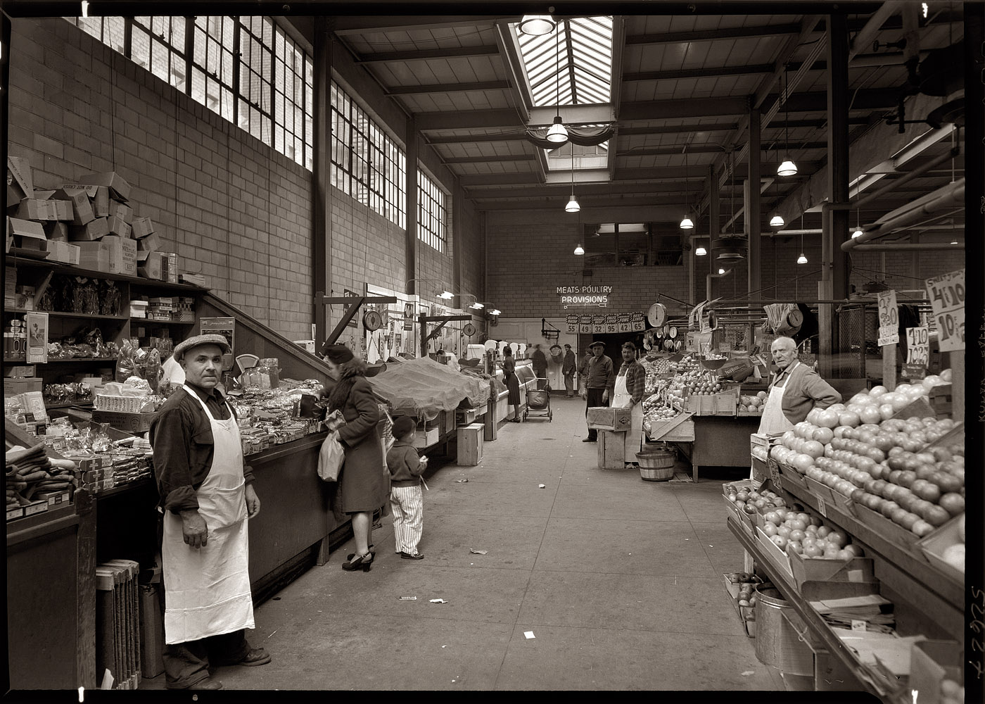 March 22, 1948. The New York City Public Market at First Avenue and East 73rd Street (?), an example of the food market in transition. A typical 19th-century market would have many separate vendors in an open-air space like a town square. By the early 1900s the open-air space had given way to separate vendors under a large shed roof with no walls, often near the train station. Here in 1948 the space is enclosed, but still with separate vendors (greengrocer, butcher, dry goods, fishmonger etc.). After the  introduction of centralized distribution and self-service for the various product categories, the individual vendors fade from the scene and the market has a new name: "super-market," now spelled without the hyphen. View full size. 5x7 safety negative by Gottscho-Schleisner.
