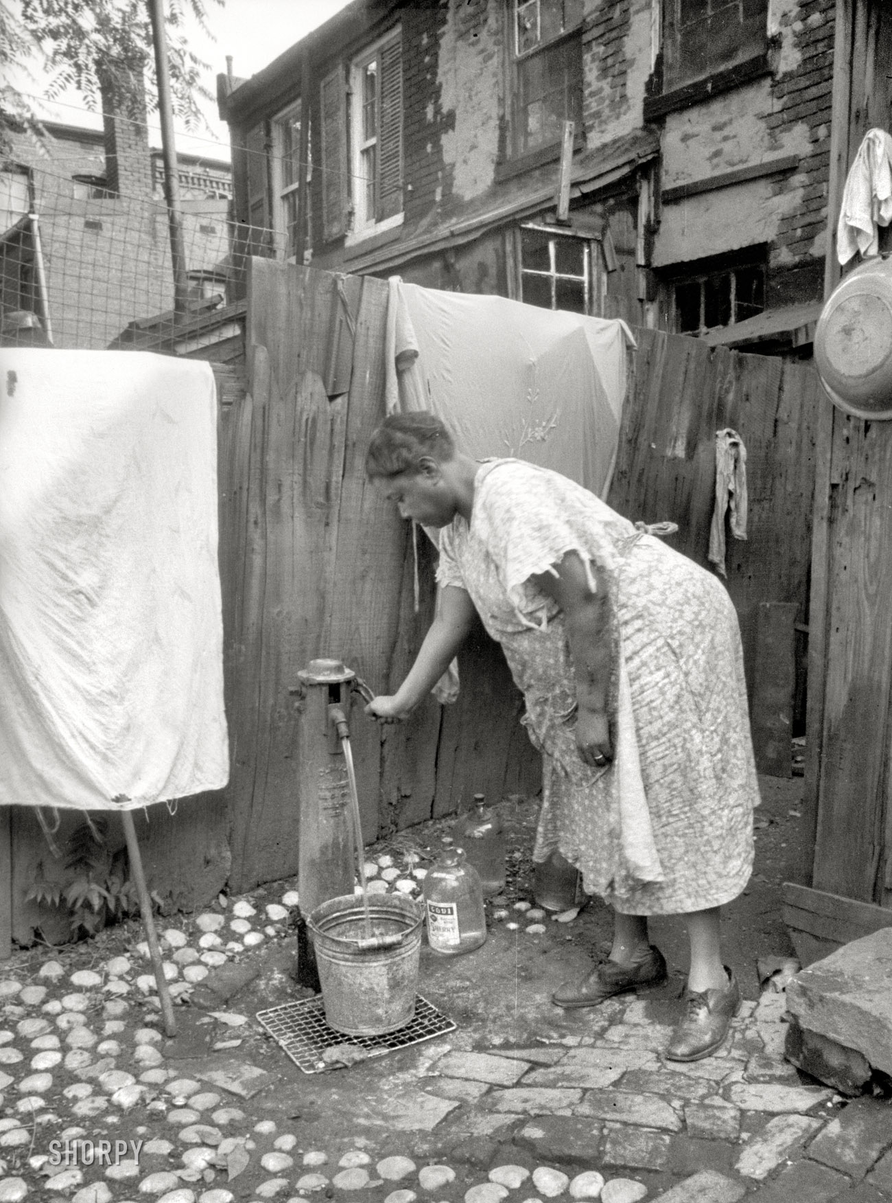 July 1935. "Outside water supply, Washington, D.C. Only source of water supply winter and summer for many houses in slum areas. In some places drainage is so poor that surplus water backs up in huge puddles." These municipal water taps (or pumps -- they have crank handles) appear in several photos from this series. I wonder if any survive. 35mm negative by Carl Mydans. View full size. 
