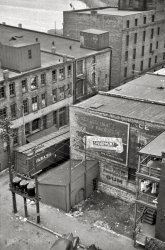 April 1940. "Dubuque, Iowa." Grit and gum in the Key City. 35mm nitrate negative by John Vachon for the Farm Security Administration. View full size.
Attention pleaseWill the person who parked their rail car in the loading zone please move it.  You are blocking traffic.
The glamor and excitement of the big city-I knew there was a reason I live in the suburbs.
After 71 yearsStill recognizable.
Just what every kid needsA Wabash boxcar in the back yard!
Looks like a brand new Ford sitting there in the alley.Don't think that a lot of people living in this neighborhood could buy a new Ford, landlord?
HO ScaleWhat an excellent subject for a railroad diorama.
Dept. of SanitationI'm impressed (or depressed?) by the amount of garbage all over the place. If there's one thing the USA has gotten better at, it is keeping the garbage off the streets and sidewalks. I've been elsewhere, and I think the USA has come a long way since this photo. 
Framed!Can anyone tell us what the purpose of the framework attached to the shed is? There are at least two wires running to the top of the framework, but no power lines or telephone lines appear to connect to it.
HopperesqueThe composition, subjec -- I wonder if the photographer was influenced by the painter Edward Hopper.
NoirThis could be the opening shot for the credits in a Robert Mitchum or Robert Ryan or Mickey Spillane thriller. It captures that grittiness and mystery very well. Who could be sitting in that car?
(The Gallery, John Vachon, Railroads)
