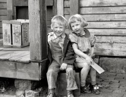 April 1940. Dubuque, Iowa. "Children who live in the slums." Our second look at this towheaded twosome, a sort of proto-Opie and his sister. 35mm nitrate negative by John Vachon for the Farm Security Administration. View full size.
Better!They look a lot happier here.  Why does that comfort me?
Also?  Check out the buckles on the little girl's shoes. FABULOUS.  I'll bet she loved them.
We Were Poorbut we didn't know any better. This photograph is definitely my favorite of the two.  It's showing them with a winning smile and a "we can make a better future" look, which is what America is all about.
Cute kidsSince the first picture of these kids I've wondered if maybe the photographer dirtied their faces up for effect. Guess I'm of a cynical nature.
[You should read up on John Vachon. - Dave]
Re: Cute KidsMaybe the dirt is the reason for their smiles, no?  All these years removed, it's not always easy to remember the fun of being carefree, running and exploring the outdoors from sun up to sundown -- but it's there, tucked away.  Something tells me there was no need for the photographer to apply any more dirt than was already on those adorable faces!
Sad or happy, these children tug at my heartstrings!
Not always a hindranceMy mother, born in 1919, grew up poor and also with a crossed eye, she always said it developed her backbone in life. My father found a doctor in 1957 to correct it. Many photographs later she was convinced it was fixed.
SweetThe reason my eyes tear up when I look at this photograph is because it makes me remember how sweet and innocent my own children where at that age.
Texas CitrusWhat a neat connection with the pictures of the other children from Weslaco &amp; Harlingen, Texas, posted earlier. That fruit box is from the Rio Grande Valley, maybe even from the farms/orchards worked by the FSA workers. Small world. 
One day at a timeI'm convinced this is a young Bonnie Franklin.
These children were loved.These children may not have lived in the best house in town, but they look well-fed and adequately clothed and shod.  Believe their parents did what it took to keep those little folks cared for and cared about.  And I weep for my little children, who always lived in a nice house and always had at least enough, but whose mother abandoned them years ago, when my daughter was 8 and my little fellow 5. 
(The Gallery, John Vachon, Kids)