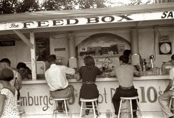Summer 1938. Hamburger stand at the Buckeye Lake amusement park near Columbus. View full size. 35mm nitrate negative by Ben Shahn, who goes on to describe the place: "Buckeye Lake is the weekend and summer months resort for all of central Ohio. Its patrons are clerks, Columbus politicians, laborers, businessmen, droves of high school and college students. The rich occupy one side of the lake, the rest rent cottages on the other side. It has an evil reputation and an evil smell. It has furnished Columbus and the neighboring small towns and cities with dancing, cottaging, swimming, etc. for several generations. This is the most unsavory place the photographer ran across in Ohio." But how are the hot dogs?