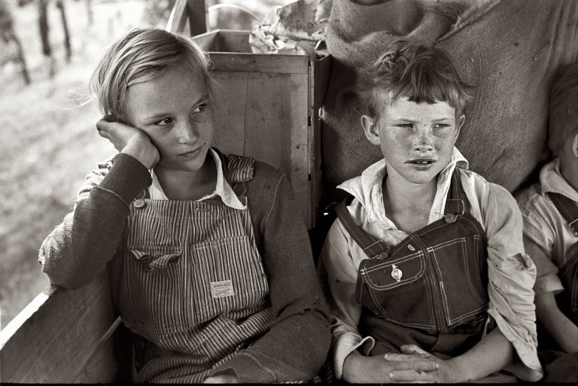 June 1939. Migrant children heading west in the back seat of the family car somewhere east of Fort Gibson in Muskogee County, Oklahoma. View full size. 35mm nitrate negative by Russell Lee for the Farm Security Administration.
