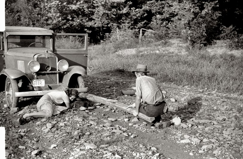 September 1940. "Mountaineer trying to change tire with a fence post as a jack. Up south fork of the Kentucky River, Breathitt County." 35mm nitrate negative by Marion Post Wolcott for the Farm Security Administration. View full size.