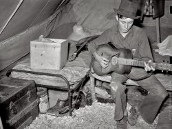 April 1939. "White migrant strawberry picker playing guitar in his tent near Hammond, Louisiana." Safety negative by Russell Lee. View full size.