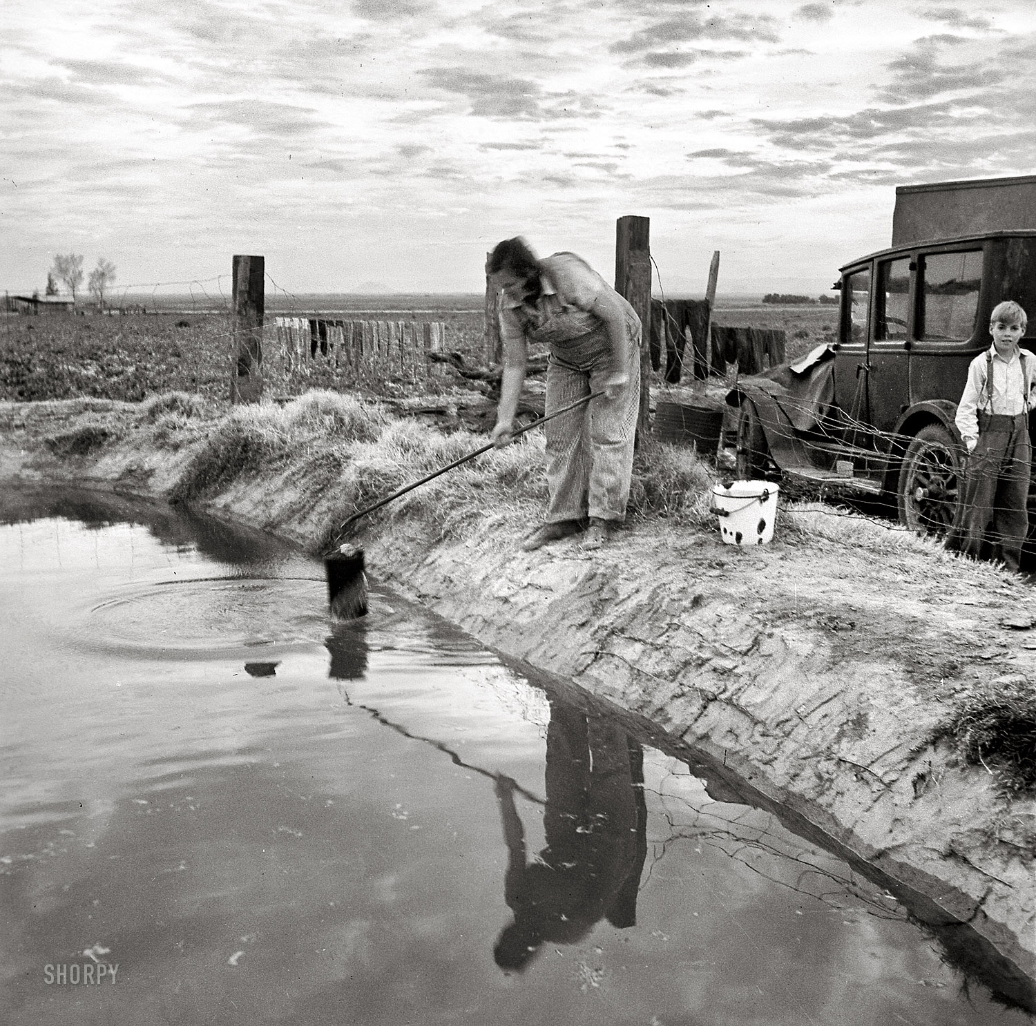 March 1937. "Water supply: Open settling basin from the irrigation ditch in a California squatter camp near Calipatria." Medium-format nitrate negative by Dorothea Lange for the Resettlement Administration. View full size.