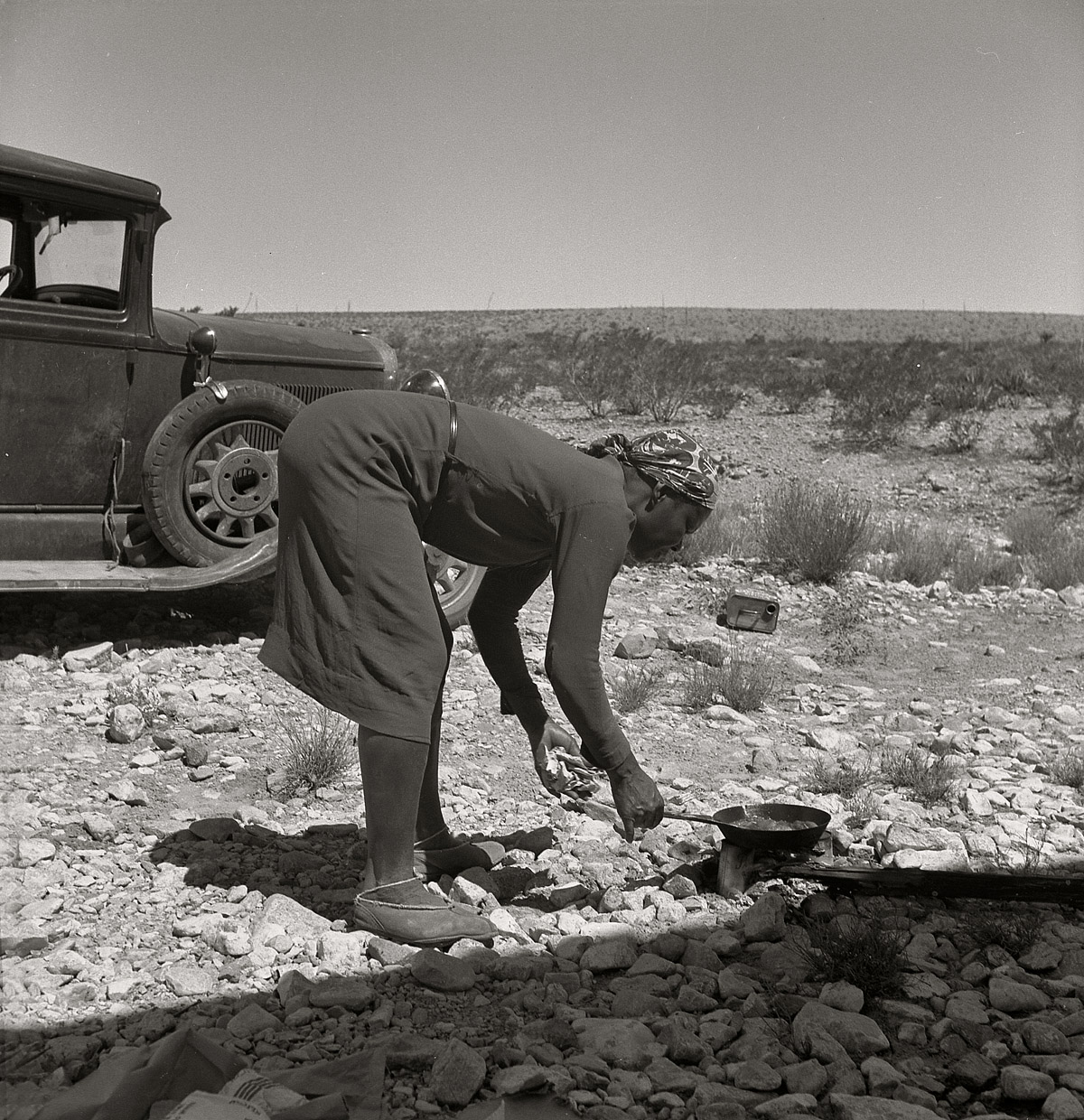 June 1938. Outskirts of El Paso, Texas. "Young Negro wife cooking breakfast. 'Do you suppose I'd be out on the highway cooking my steak if I had it good at home?' Occupations: hotel maid, cook, laundress." Medium-format nitrate negative by Dorothea Lange for the Farm Security Administration. View full size.  