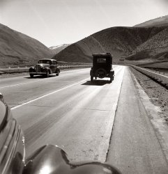 U.S. 99 in Kern County on the Tehachapi Ridge. February 1939. Migrant workers travel seasonally back and forth between the Imperial Valley and San Joaquin Valley over this ridge. View full size. Photograph by Dorothea Lange. (The billboard up ahead: "76 miles to GRAPEVINE air cooled cafe.")