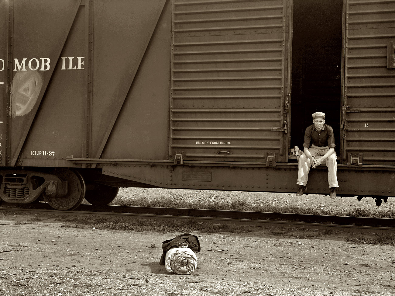 February 1939. Calipatria, Imperial Valley. Car on siding across tracks from pea packing plant. Twenty-five year old itinerant, originally from Oregon. "On the road eight years, all over the country, every state in the union, back and forth, pick up a job here and there, traveling all the time." View full size.  Medium format nitrate negative by Dorothea Lange for the Farm Security Administration.