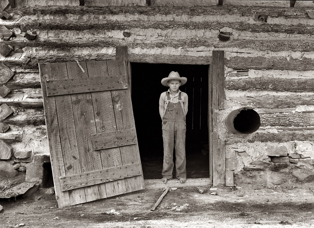 July 1939. Farm boy in the doorway of a tobacco barn. Person County, North Carolina. View full size. Photograph by Dorothea Lange.
