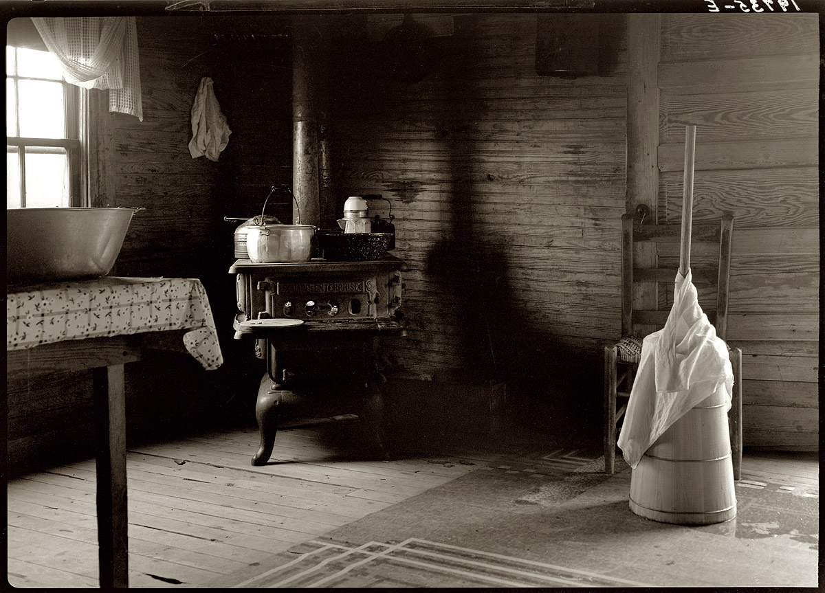 July 1939. Corner of a sharecropper's kitchen showing stove and butter churn. Person County, North Carolina. View full size. Photograph by Dorothea Lange.