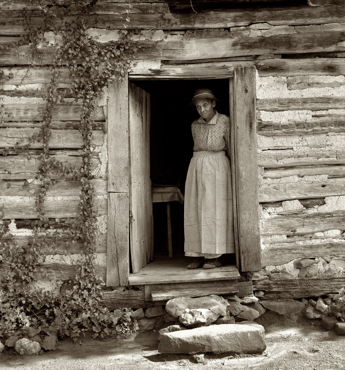 July 1939. Caroline Atwater standing in the kitchen door of her log house. Orange County, North Carolina. View full size. Medium-format nitrate negative by Dorothea Lange for the Farm Security Administration.