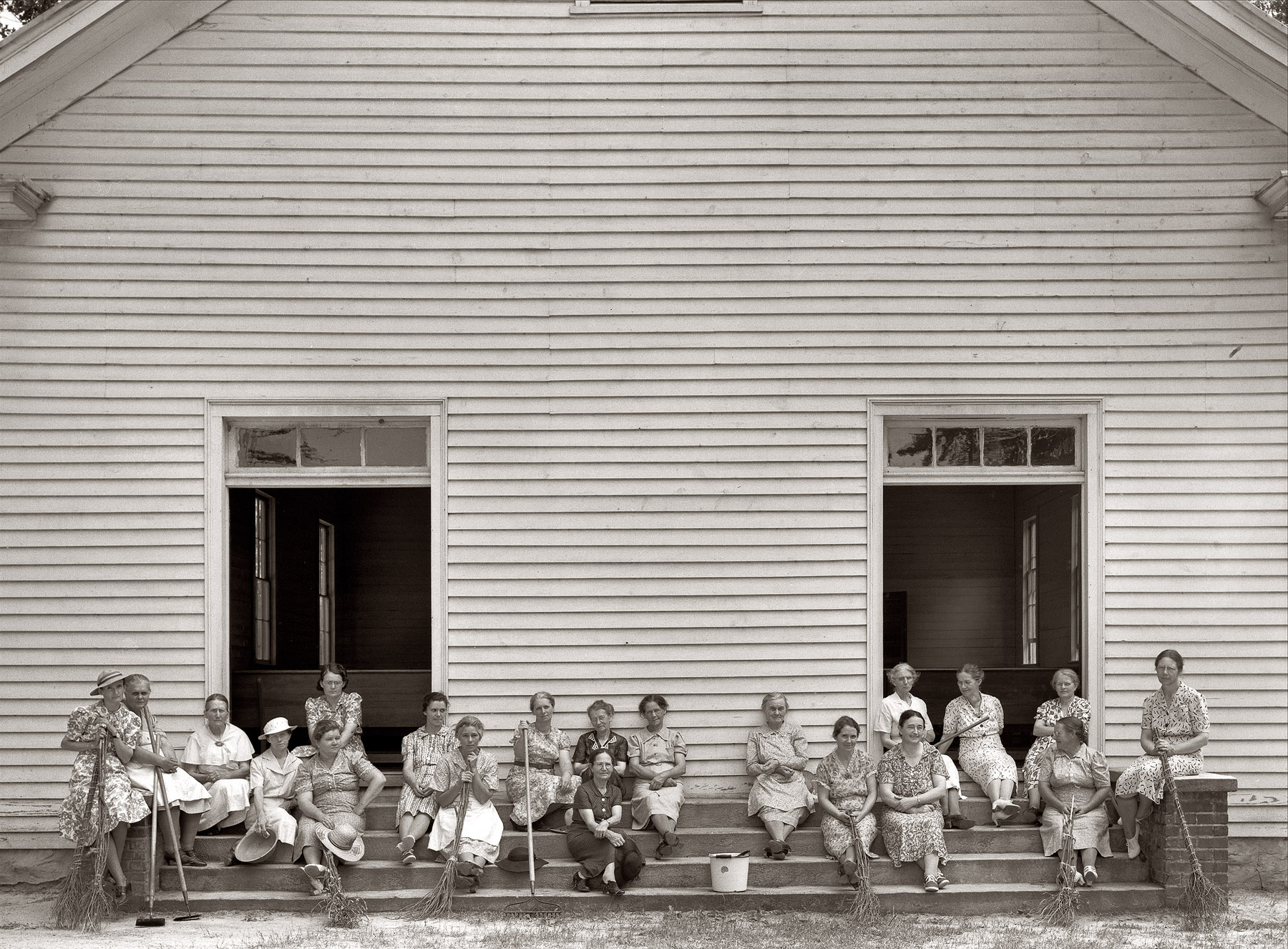 July 1939. Women of the congregation of Wheeler's Church on steps with brooms and buckets on annual clean up day. Gordonton, North Carolina. View full size.