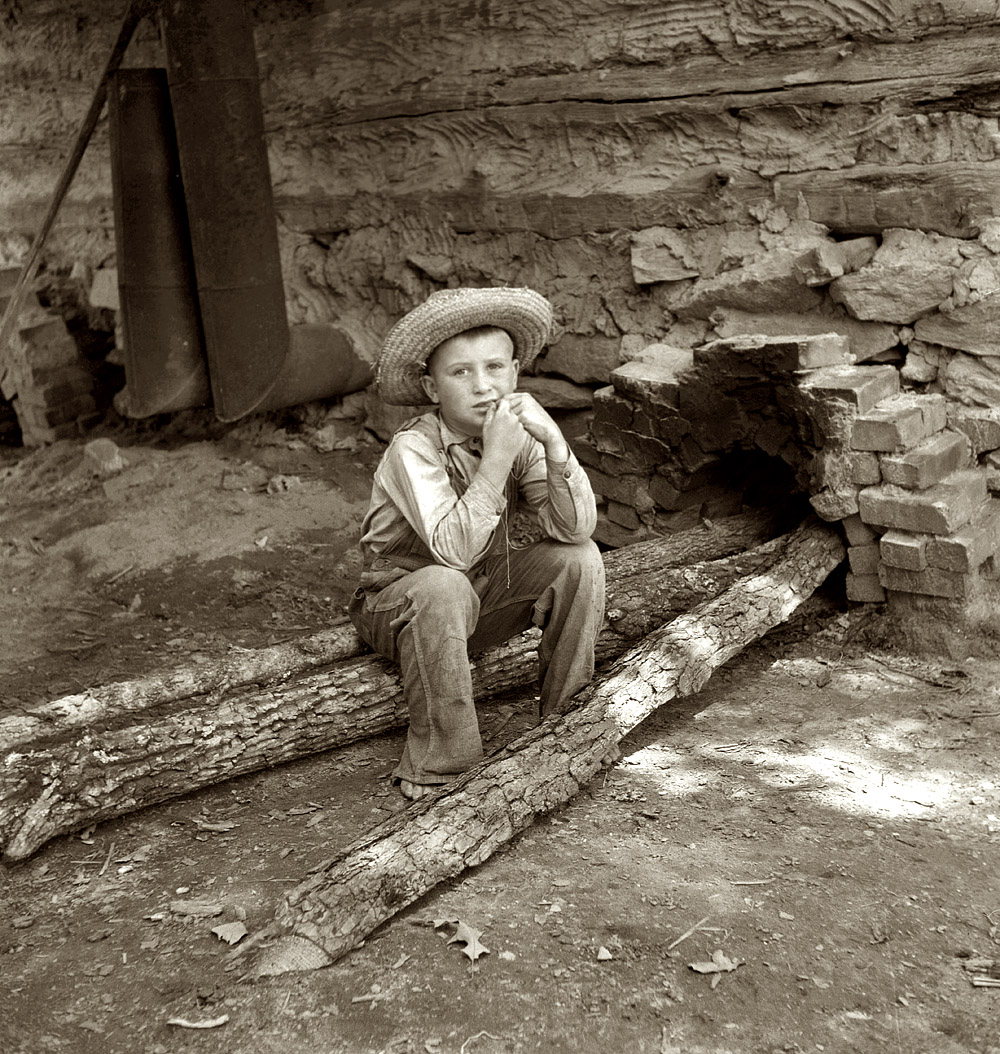 July 1939. "Ten-year-old son of tobacco sharecropper can do a 'hand's work' at harvest time." Seen here feeding logs into the fire next to flue of the curing barn. Granville County, North Carolina. View full size.  Medium-format nitrate negative by Dorothea Lange for the Farm Security Administration.