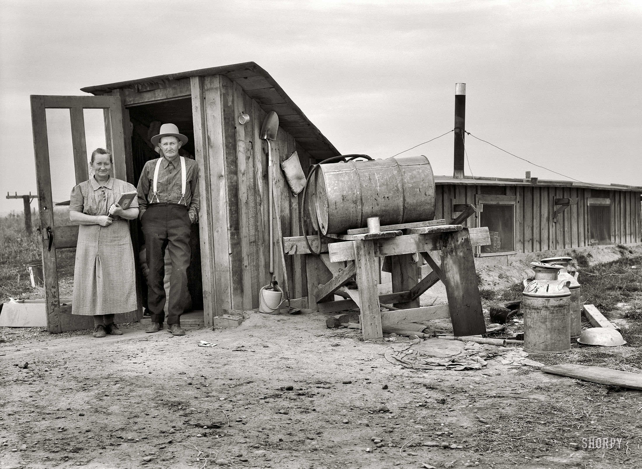October 1939. "Mr. and Mrs. Wardlaw at entrance to their dugout basement home. Dead Ox Flat, Malheur County, Oregon." Medium-format nitrate negative by Dorothea Lange for the Resettlement Administration. View full size.