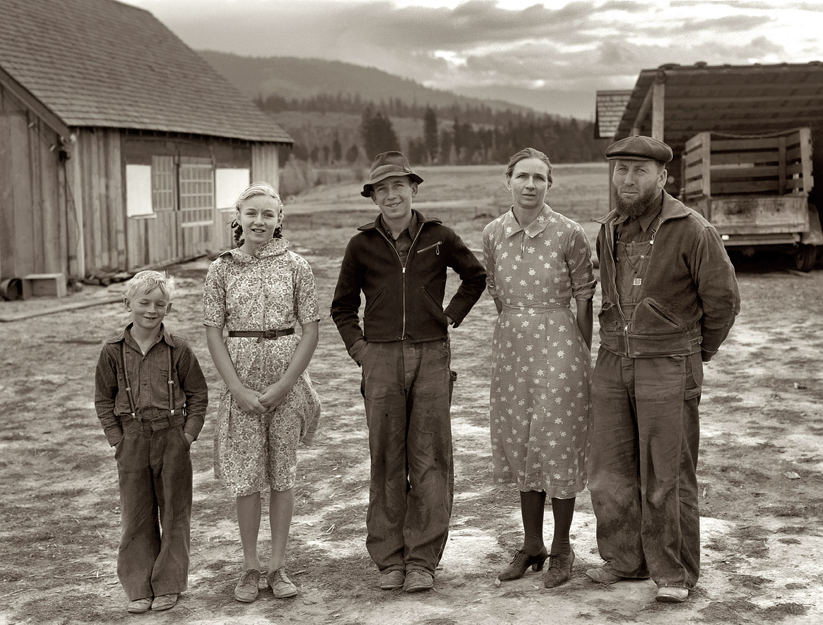 October 1939. The Unruf family. Mennonite wheat farmers from Kansas, now developing a stump ranch in Boundary County, Idaho. The mother, father and hardworking 15-year-old son with other children in yard before the barn. Father and son have cleared 30 acres of raw stump land in three years.  Medium-format nitrate negative by Dorothea Lange for the FSA. View full size.